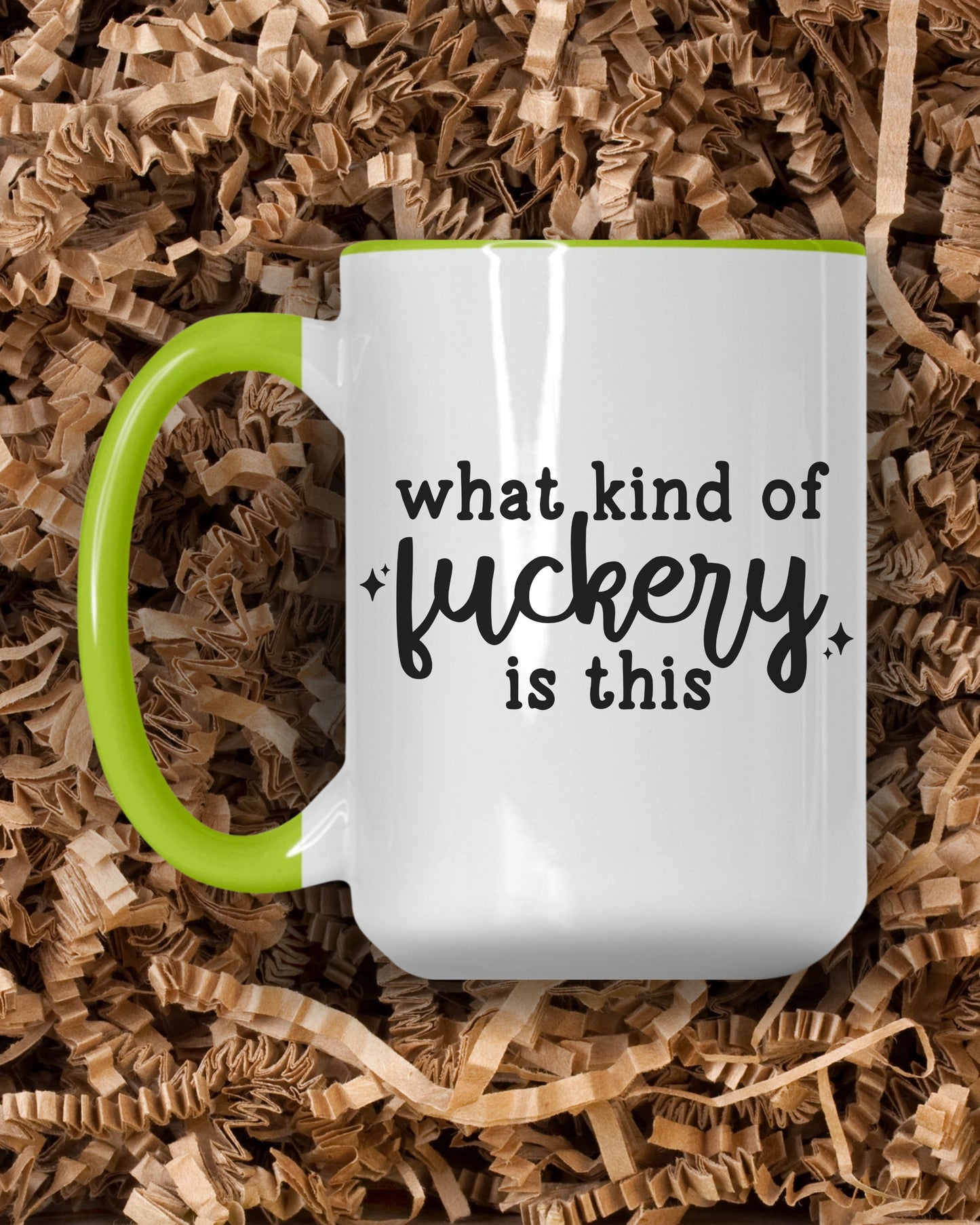 White mug with black text and green handle on brown shredded paper