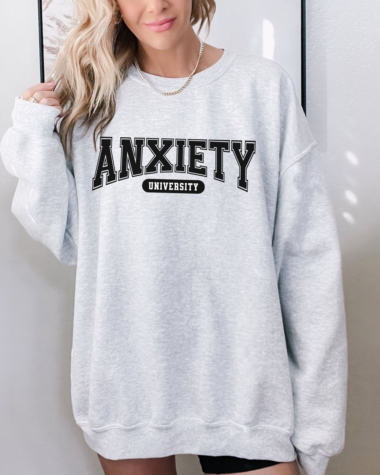Person wearing a gray sweatshirt with 'ANXIETY UNIVERSITY' text.