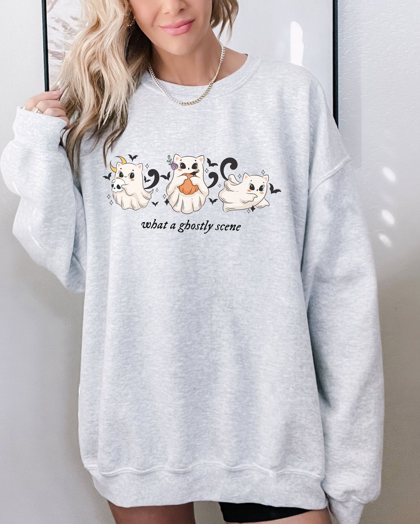 Gray sweatshirt with ghost and pumpkin design worn by a person against a white background