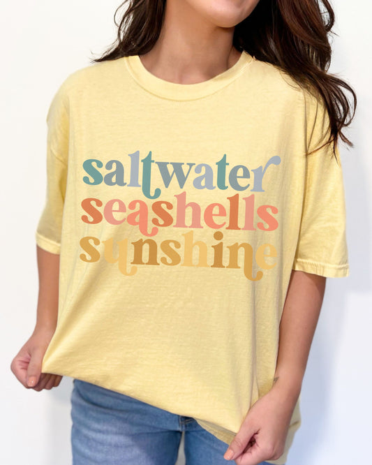 woman wearing beach vibes shirt with saltwater seashells sunshine design