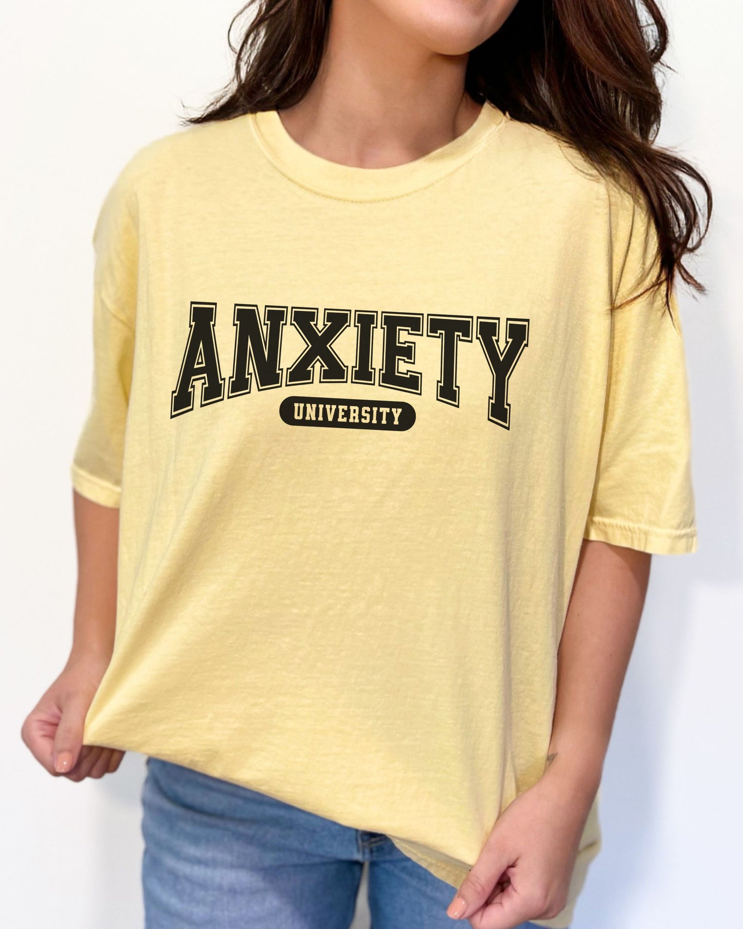 Person wearing a yellow t-shirt with 'ANXIETY UNIVERSITY' text on a white background