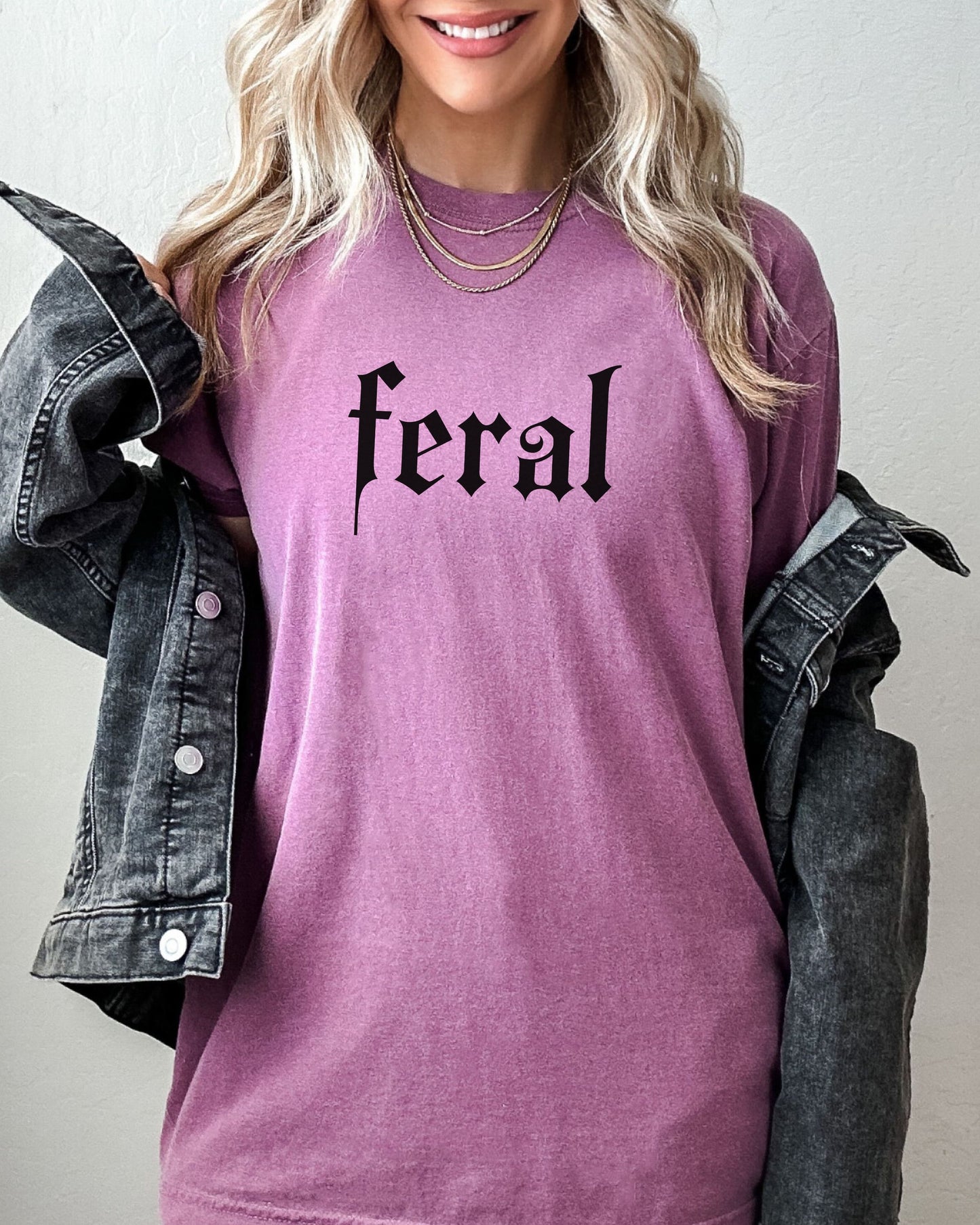 grunge aesthetic feral t-shirt in black font worn by model, in color berry