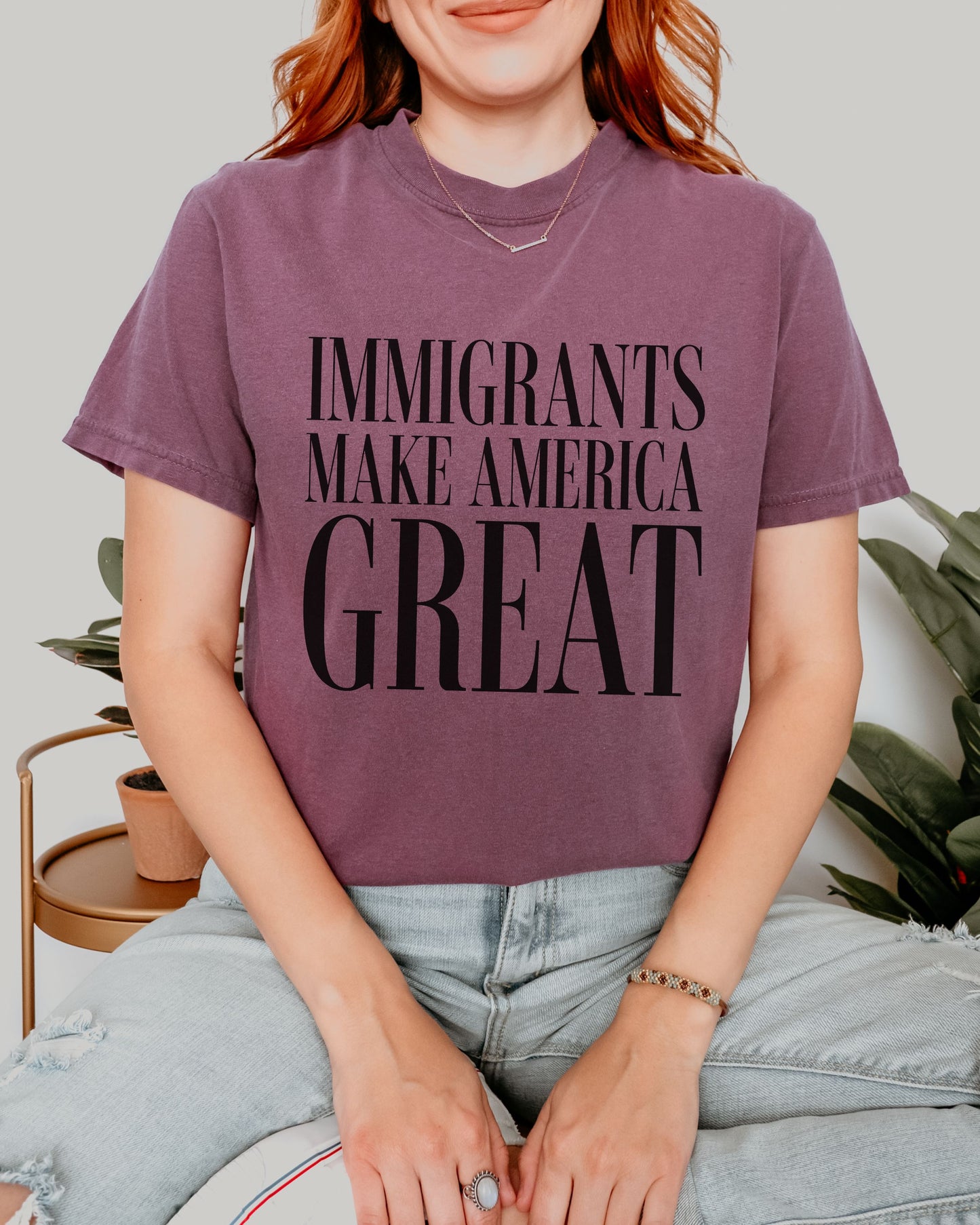 Person wearing a purple t-shirt with 'IMMIGRANTS MAKE AMERICA GREAT' text.