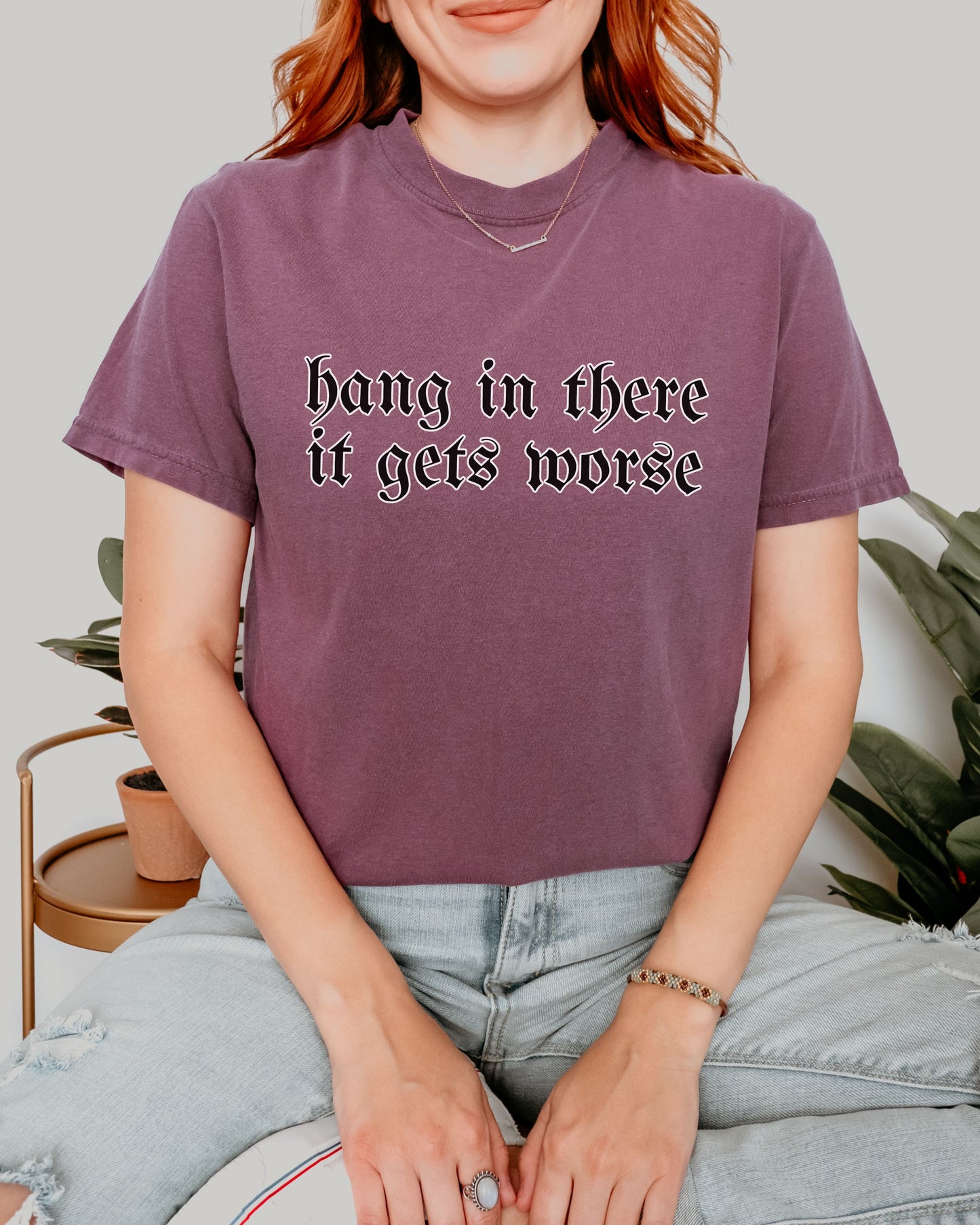 Person wearing a purple t-shirt with text, sitting on a couch.