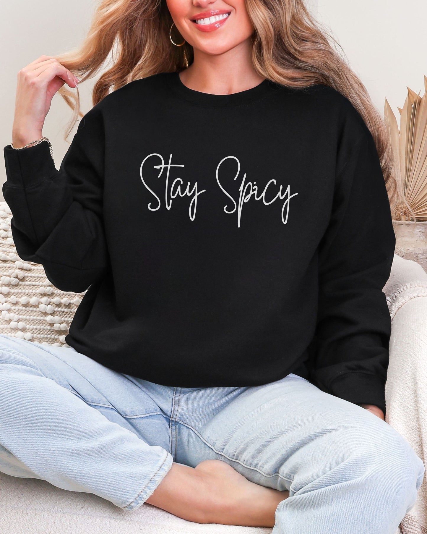 Person wearing a black sweatshirt with 'Stay Spicy' text, sitting on a couch.
