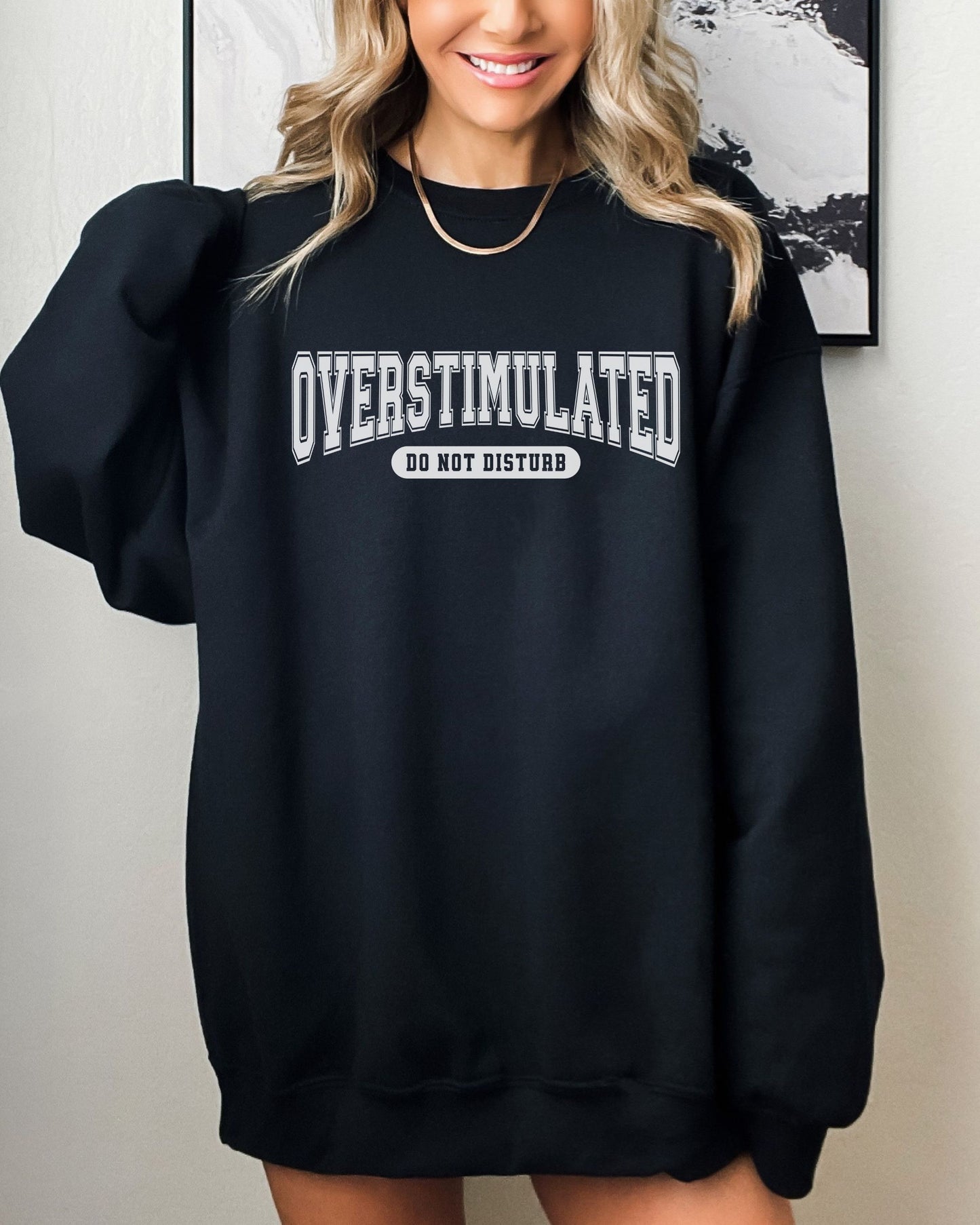 Person wearing a black sweatshirt with 'OVERSTIMULATED DO NOT DISTURB' text.