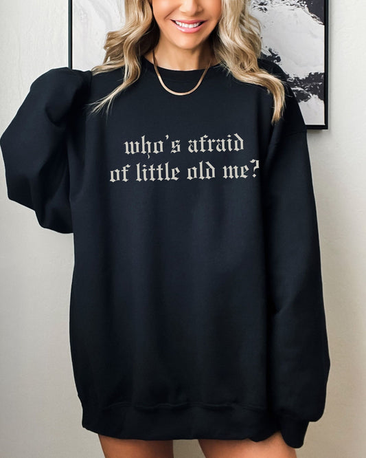 Person wearing a black sweatshirt with text, standing against a neutral background