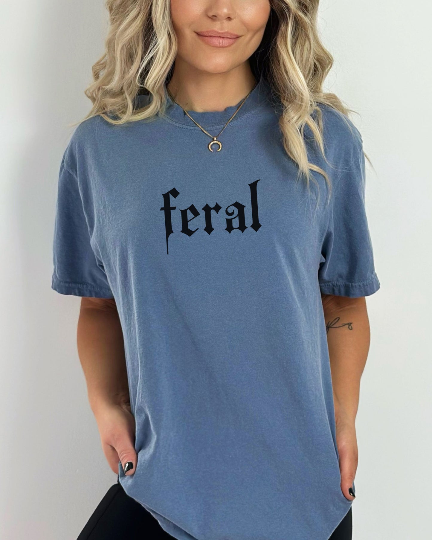 grunge aesthetic feral t-shirt in black font worn by model, in color blue jean