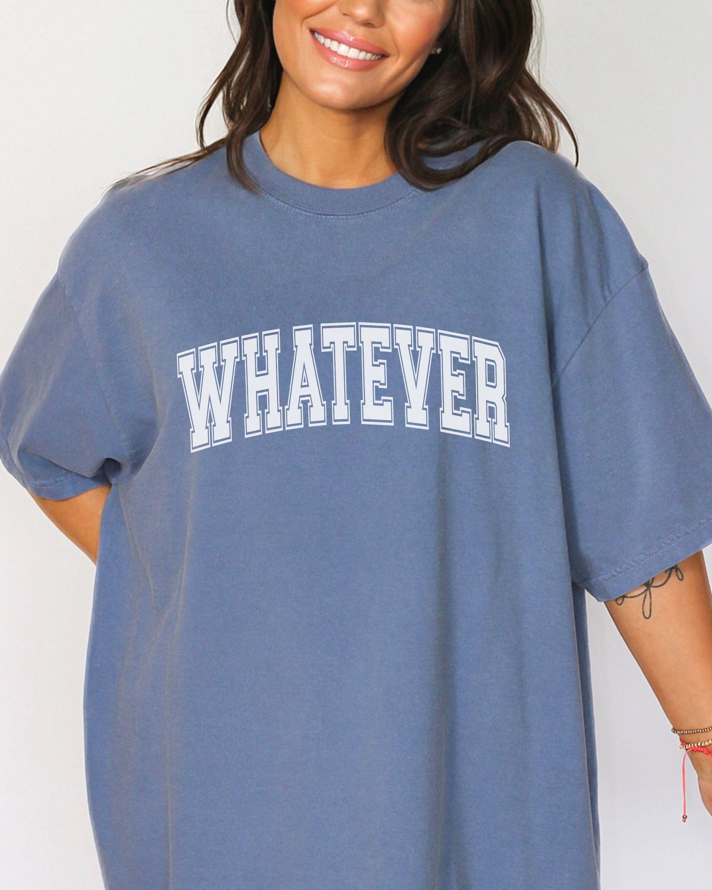 Blue t-shirt with 'WHATEVER' text worn by a person on a plain background