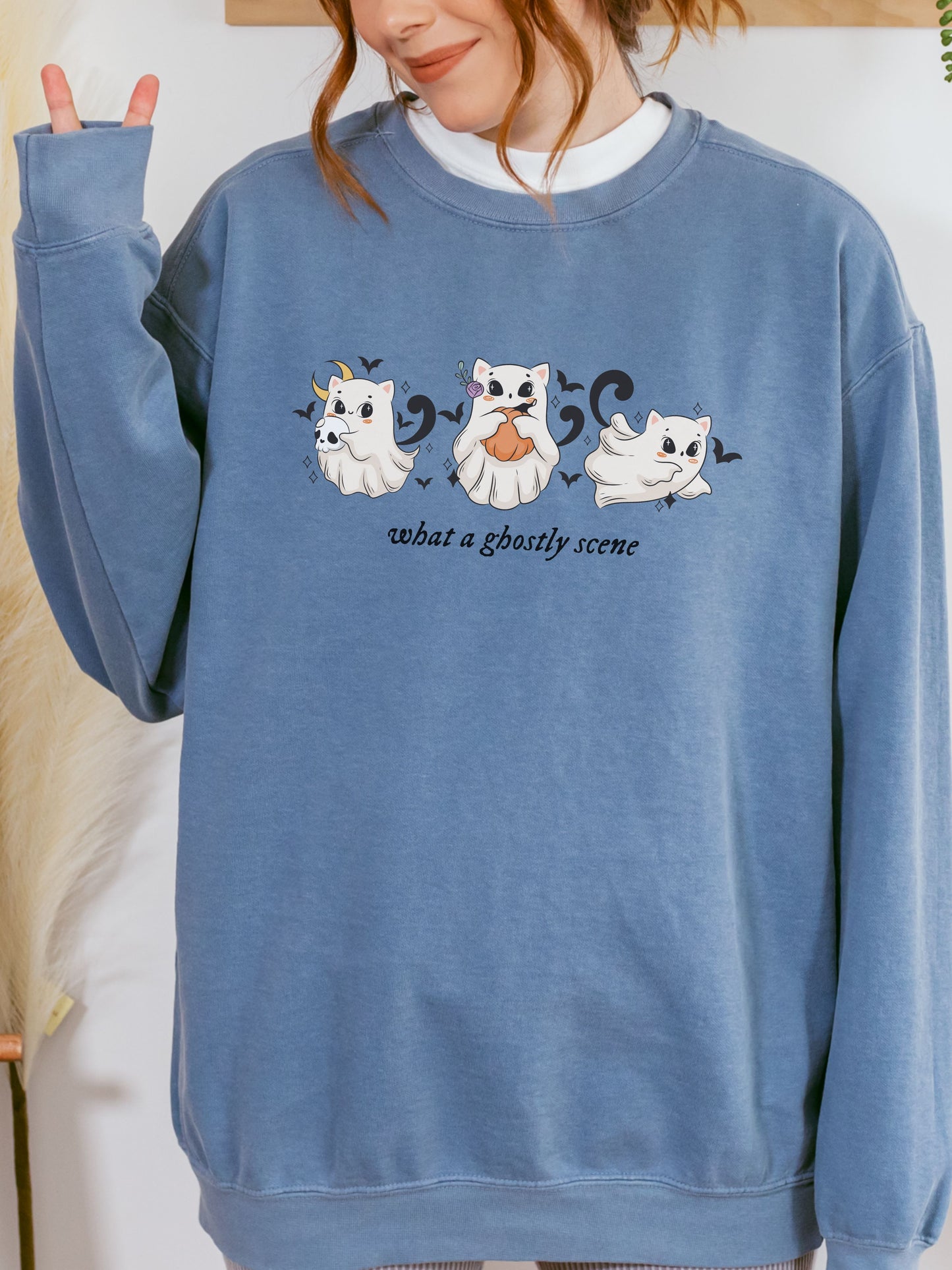 Person wearing a blue sweatshirt with ghost illustrations and text.