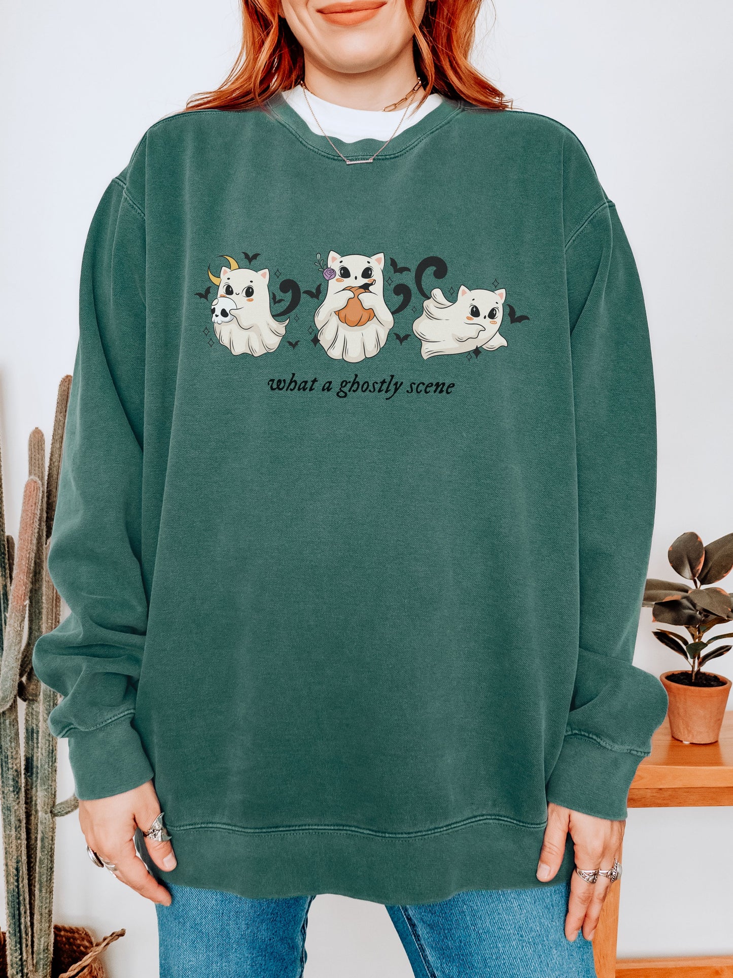 Person wearing a green sweatshirt with ghost illustrations and text.