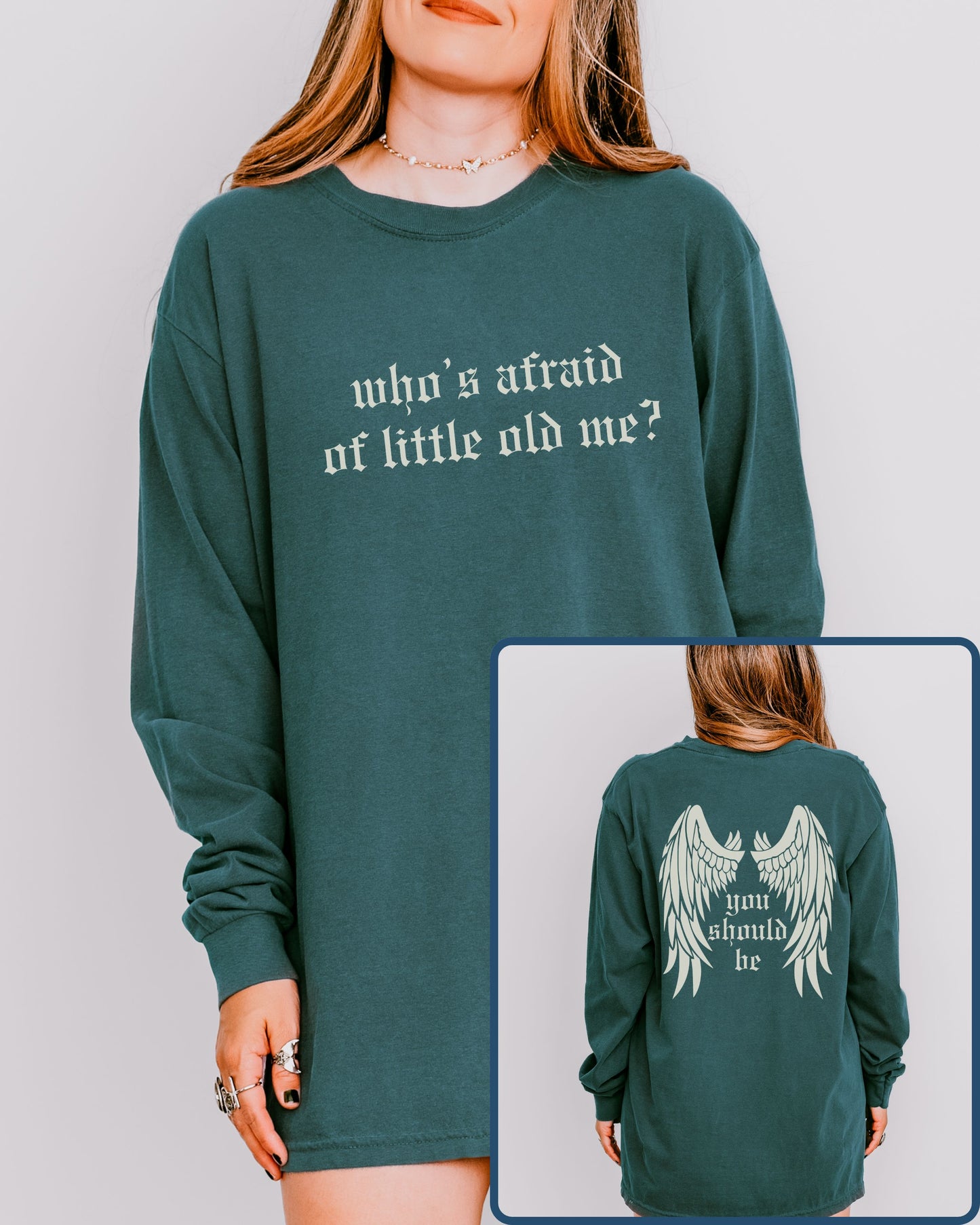 Green long-sleeve shirt with text 'who's afraid of little old me?' on front, inset showing back with wings and text.