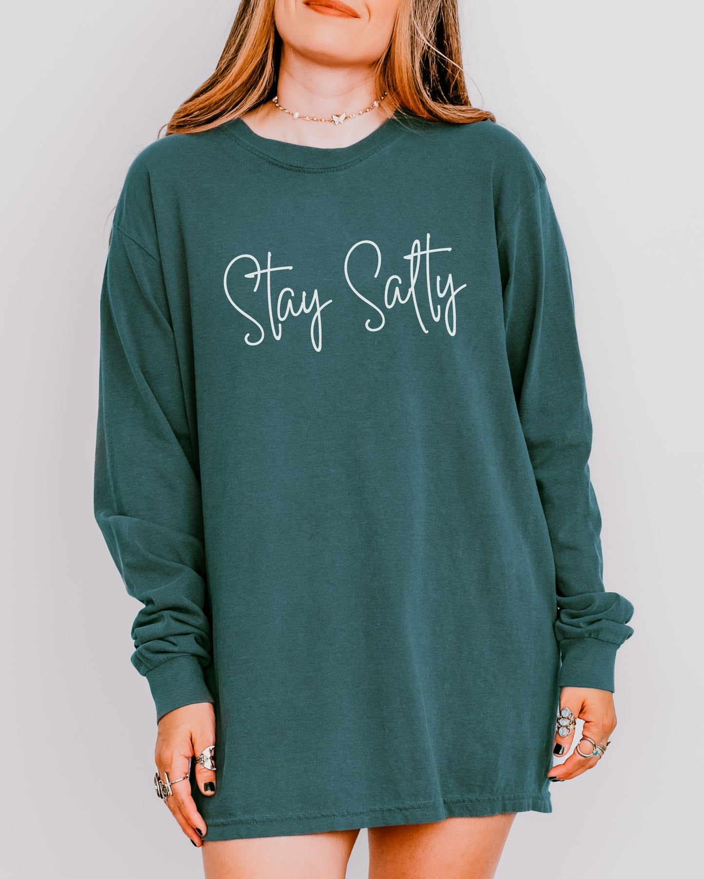 Green long-sleeve shirt with 'Stay Salty' text worn by a person on a plain background