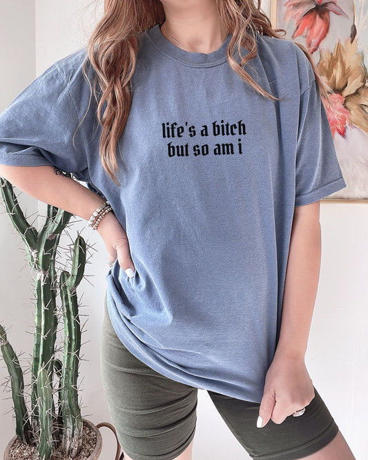 Person wearing a blue t-shirt with text, standing next to a cactus plant.