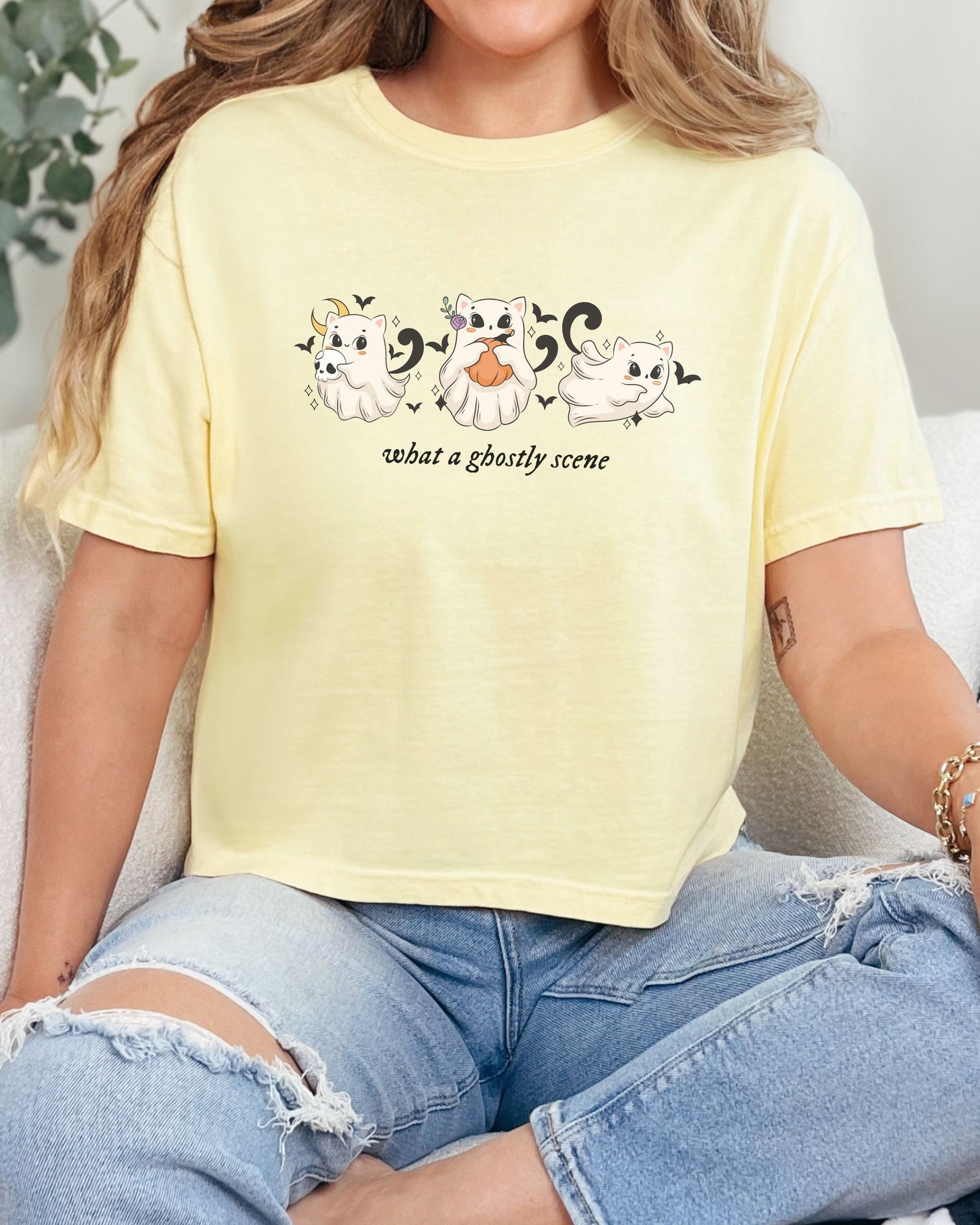 Person wearing a yellow t-shirt with ghost illustrations and text.