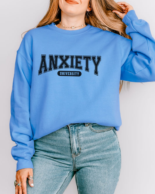 Person wearing a blue sweatshirt with 'ANXIETY UNIVERSITY' text on a plain background