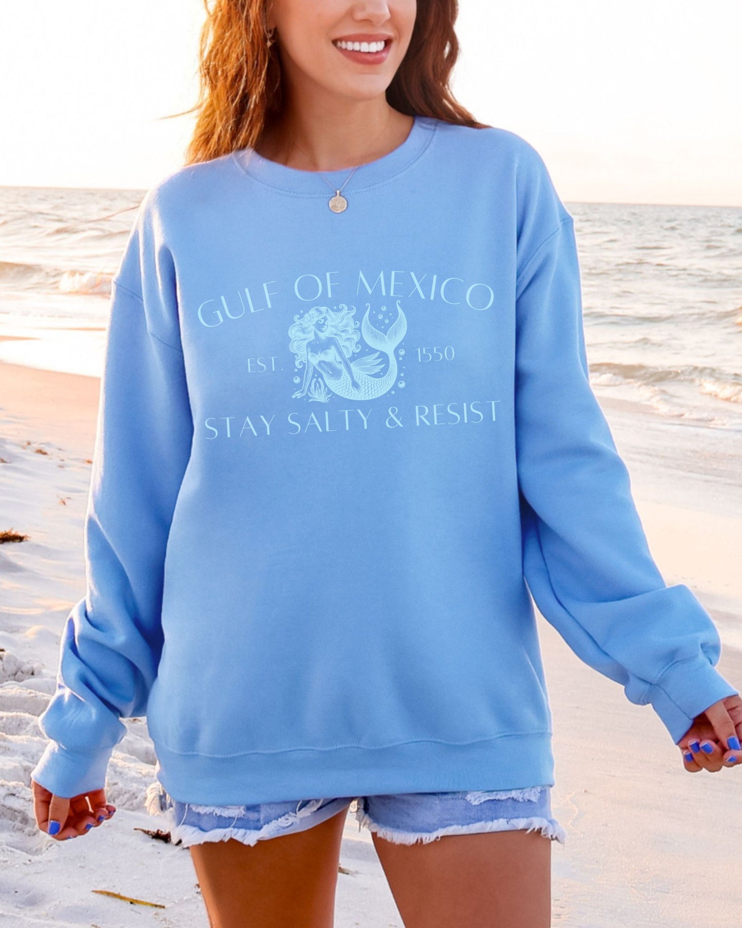 Person wearing a blue sweatshirt with 'Gulf of Mexico' text on a beach