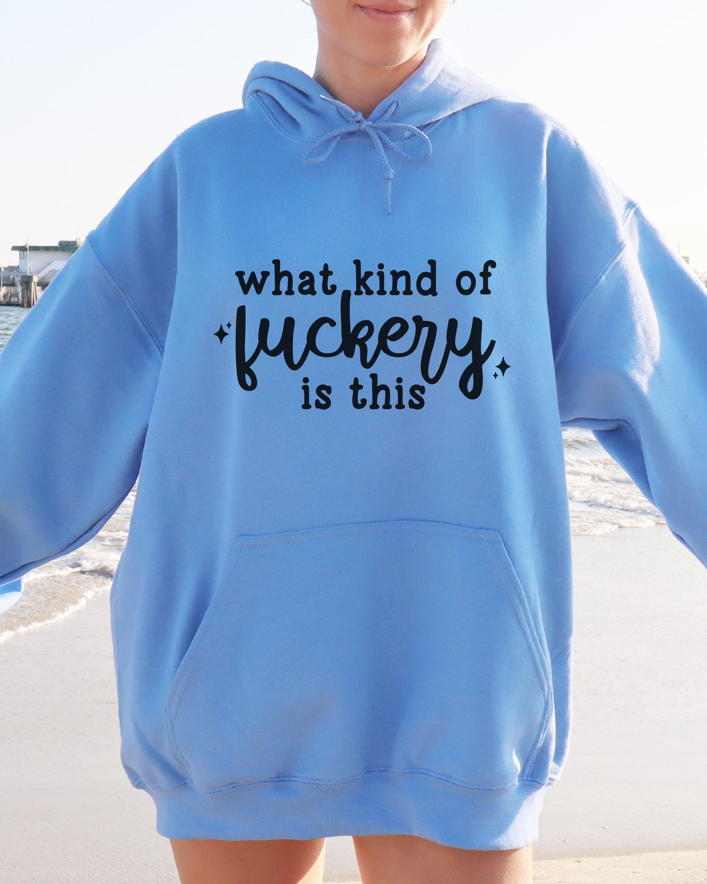 Person wearing a blue hoodie with text on a beach