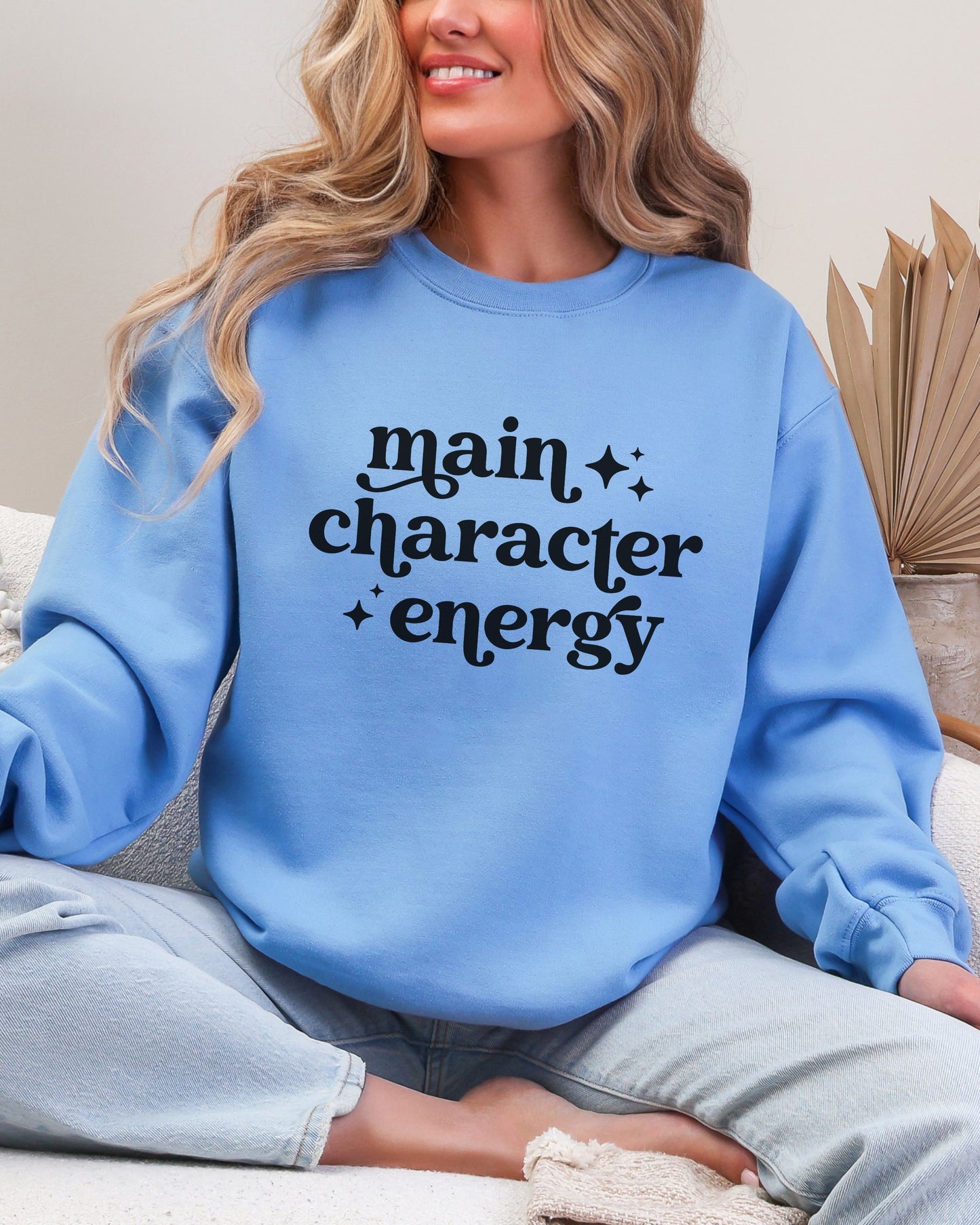 Person wearing a blue sweatshirt with 'main character energy' text.