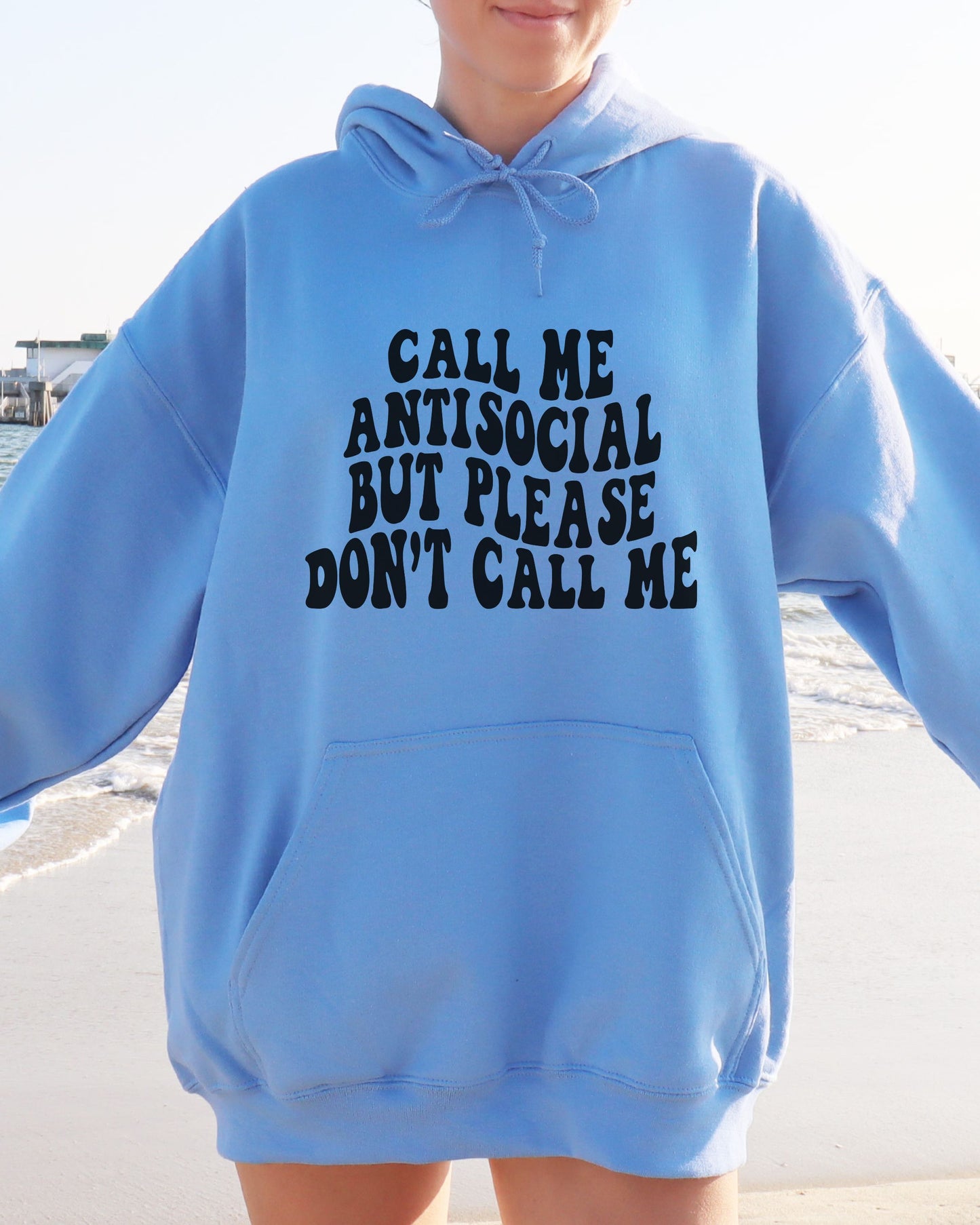 Person wearing a blue hoodie with text on a beach