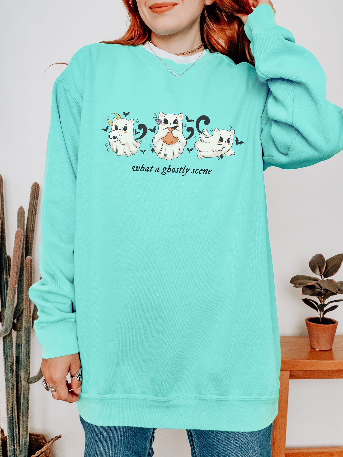 Person wearing a light blue sweatshirt with ghost illustrations and text.