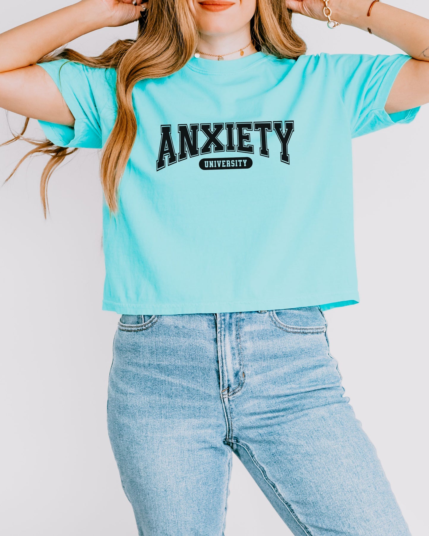 Person wearing a light blue t-shirt with 'ANXIETY UNIVERSITY' text on a plain background
