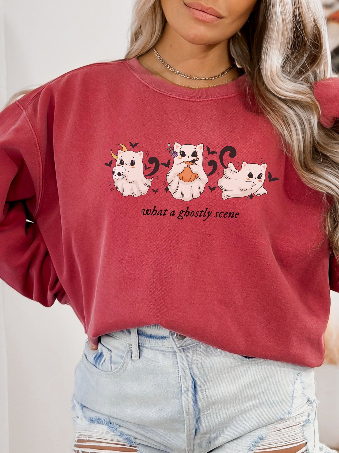 Person wearing a red sweatshirt with ghost illustrations and text.