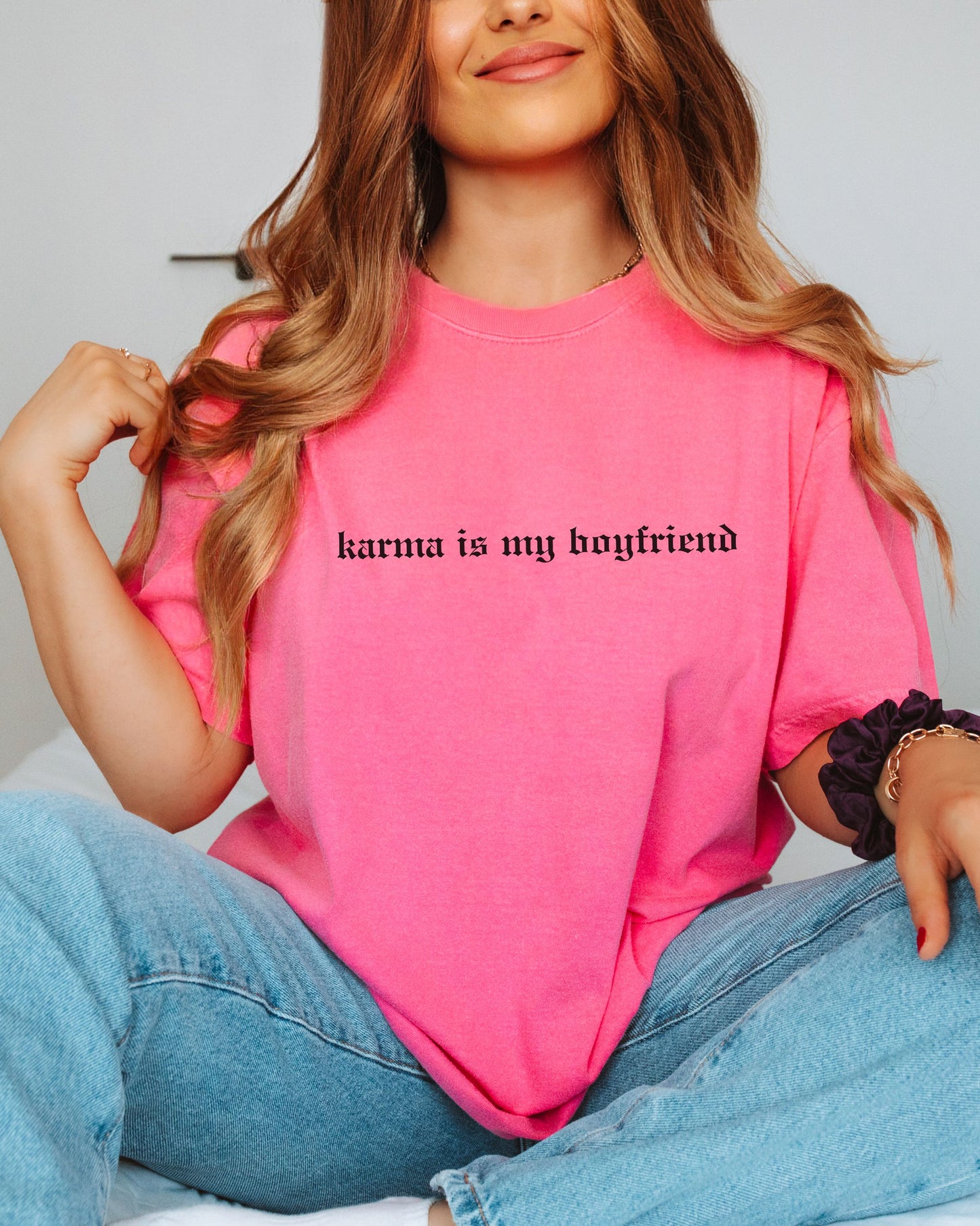 Person wearing a pink t-shirt with 'karma is my boyfriend' text.