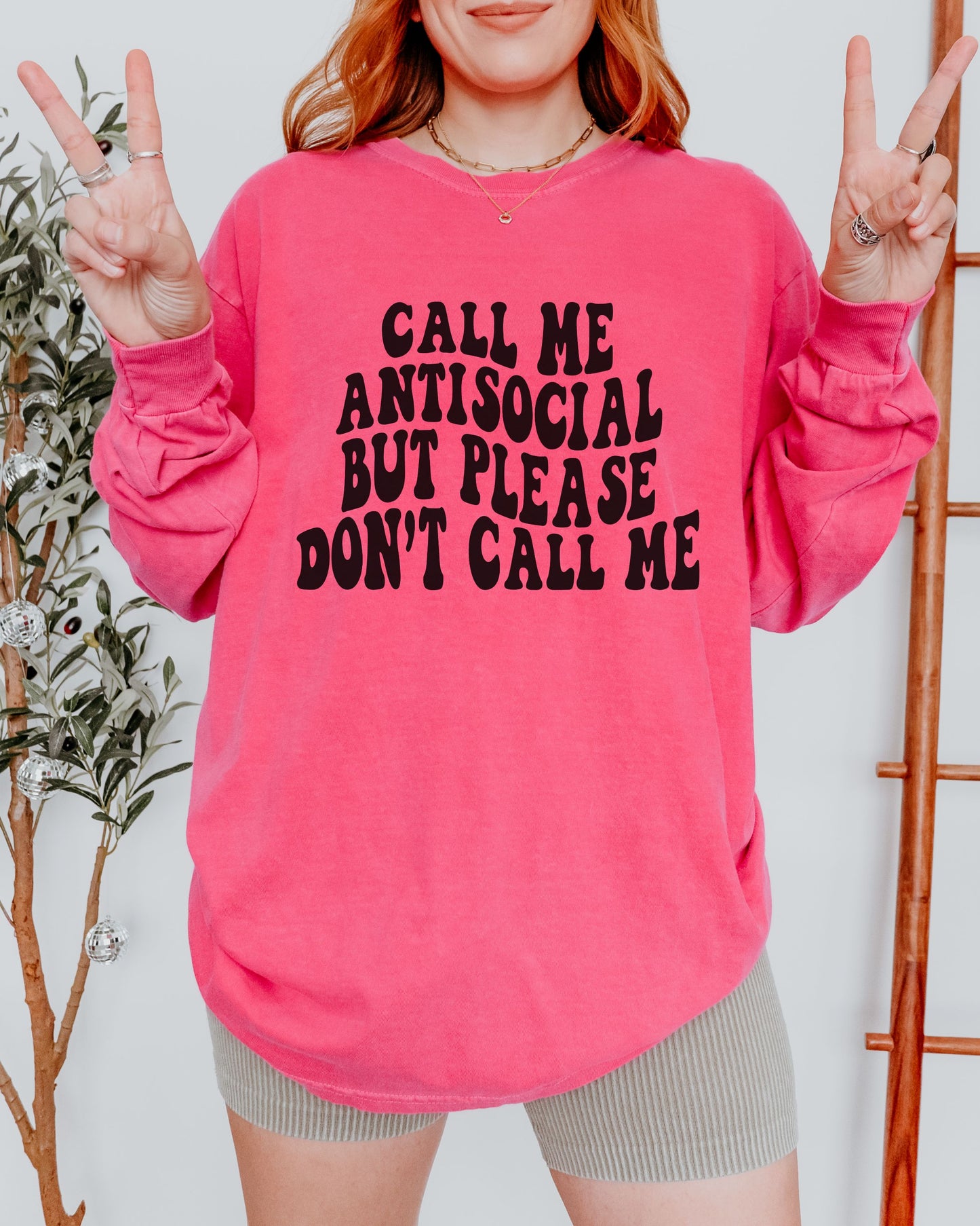Person wearing a pink sweatshirt with text, making peace signs.