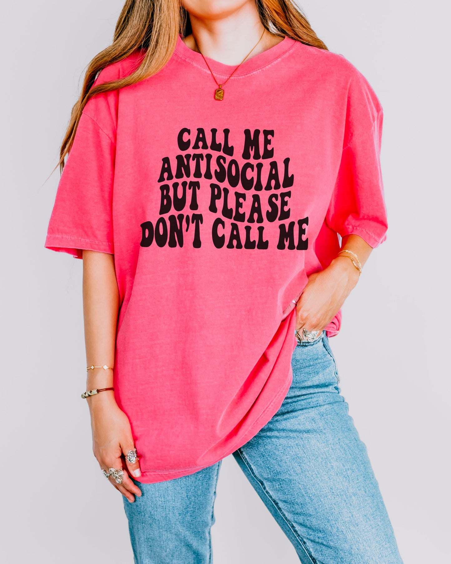 Person wearing a pink t-shirt with text and blue jeans on a plain background