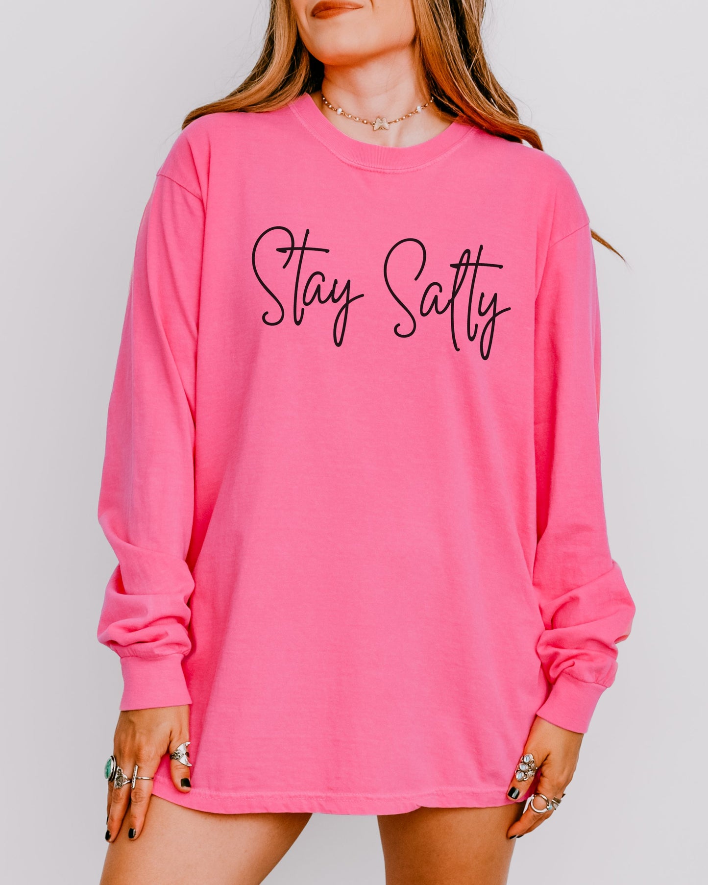 Person wearing a pink long-sleeve shirt with 'Stay Salty' text on a plain background