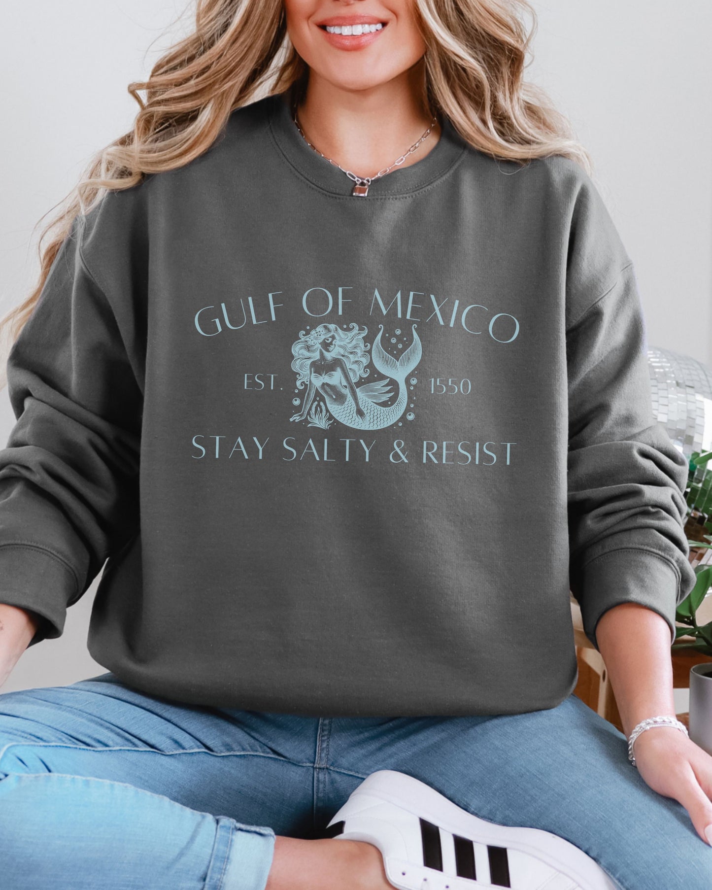 Person wearing a gray sweatshirt with 'Gulf of Mexico' text and design.