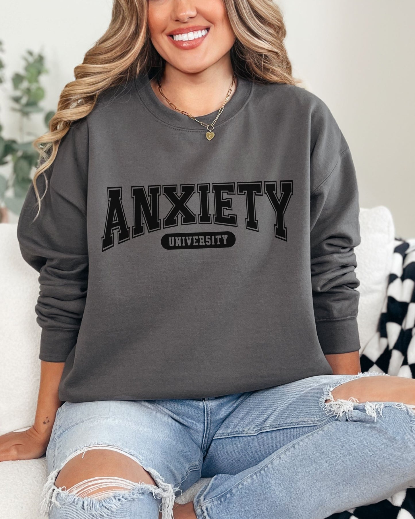 Person wearing a gray sweatshirt with 'ANXIETY UNIVERSITY' text, sitting on a couch.