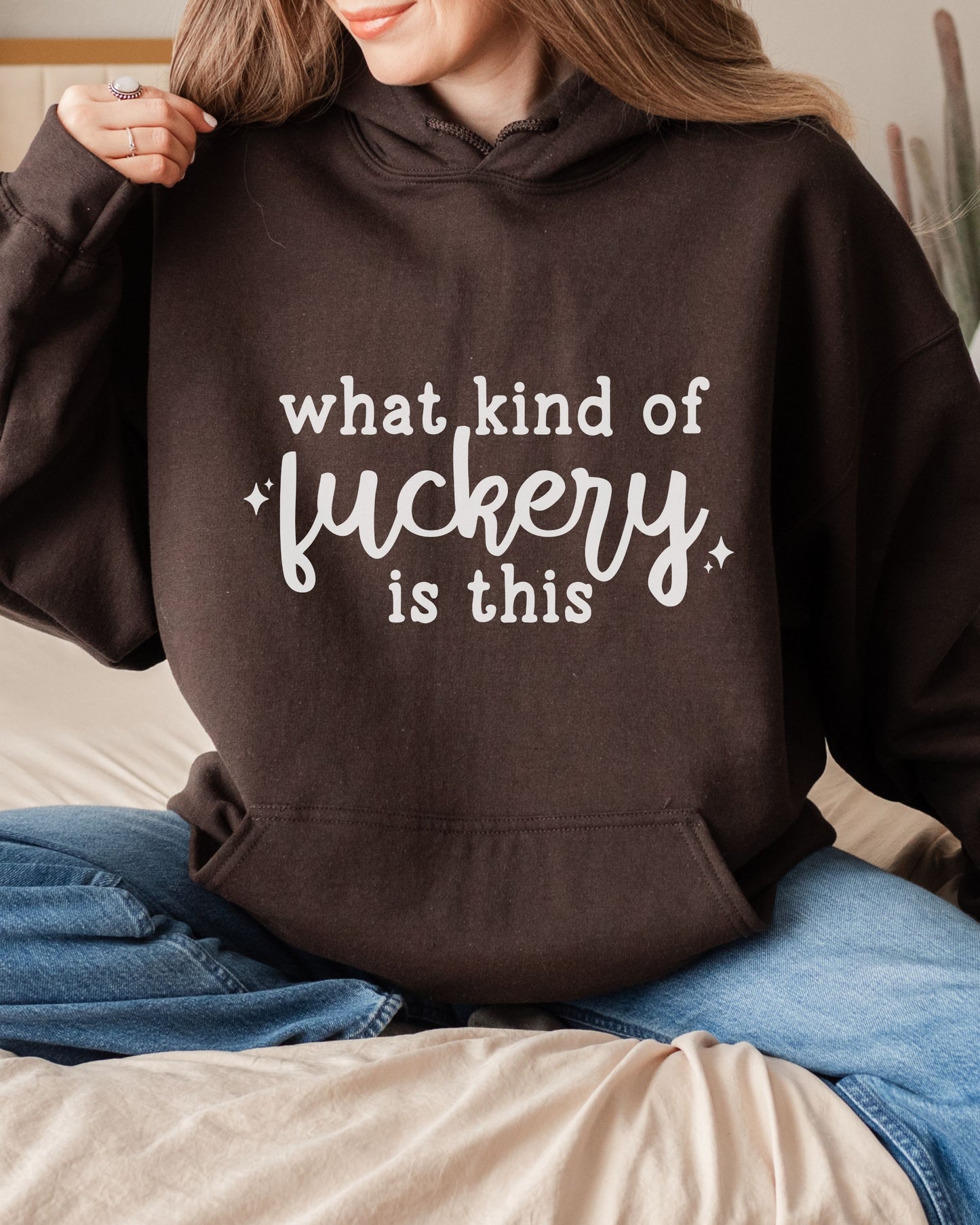 Person wearing a brown hoodie with text sitting on a couch.