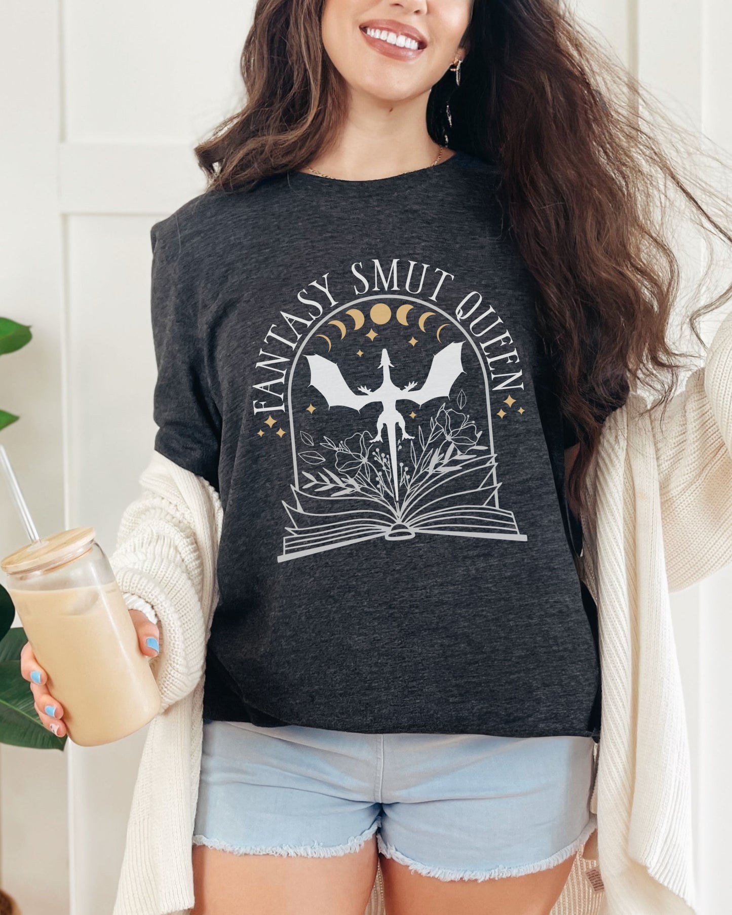 Woman wearing a dark gray t-shirt with 'Fantasy Smut Queen' design, holding a drink.