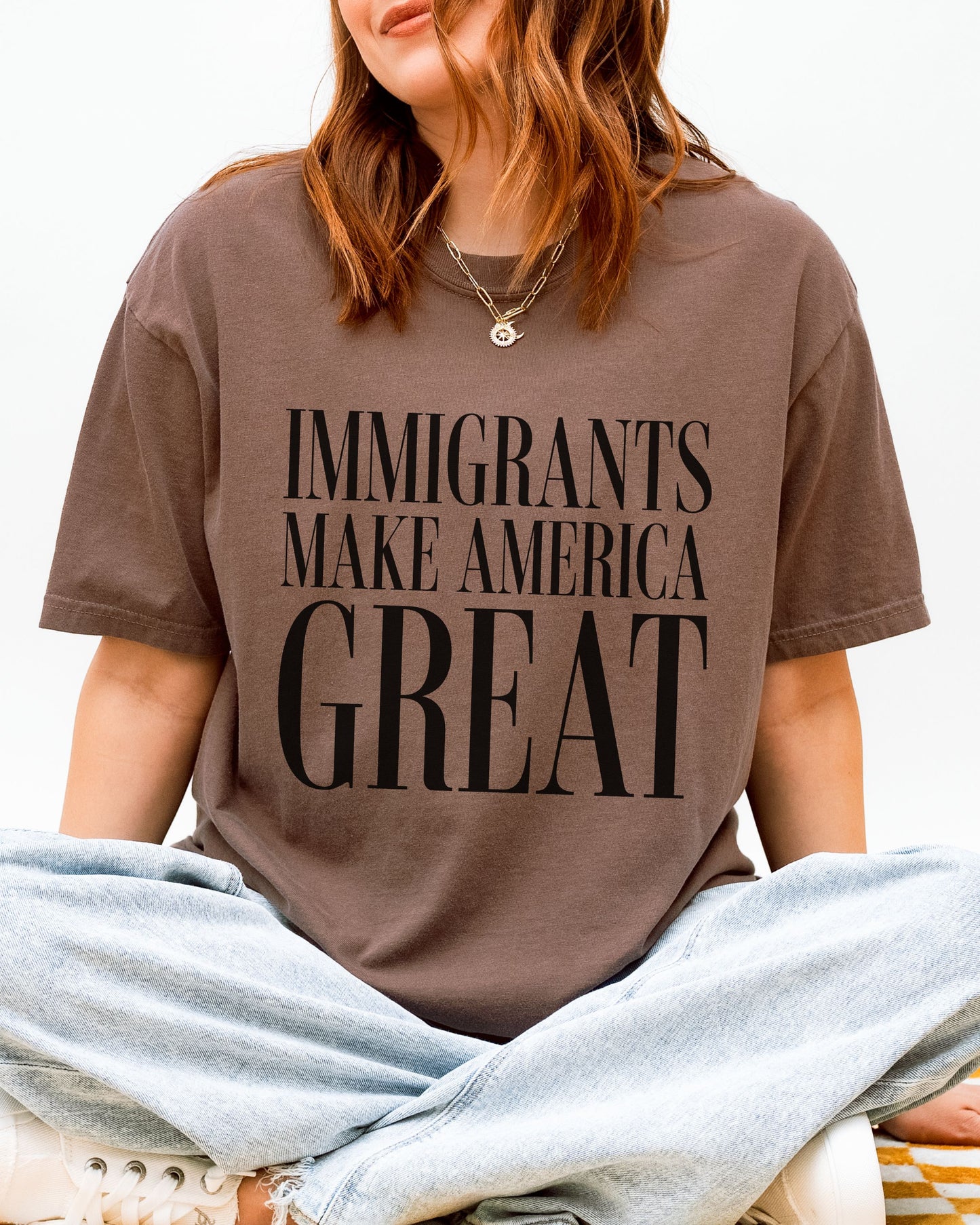Person wearing a brown t-shirt with 'IMMIGRANTS MAKE AMERICA GREAT' text.