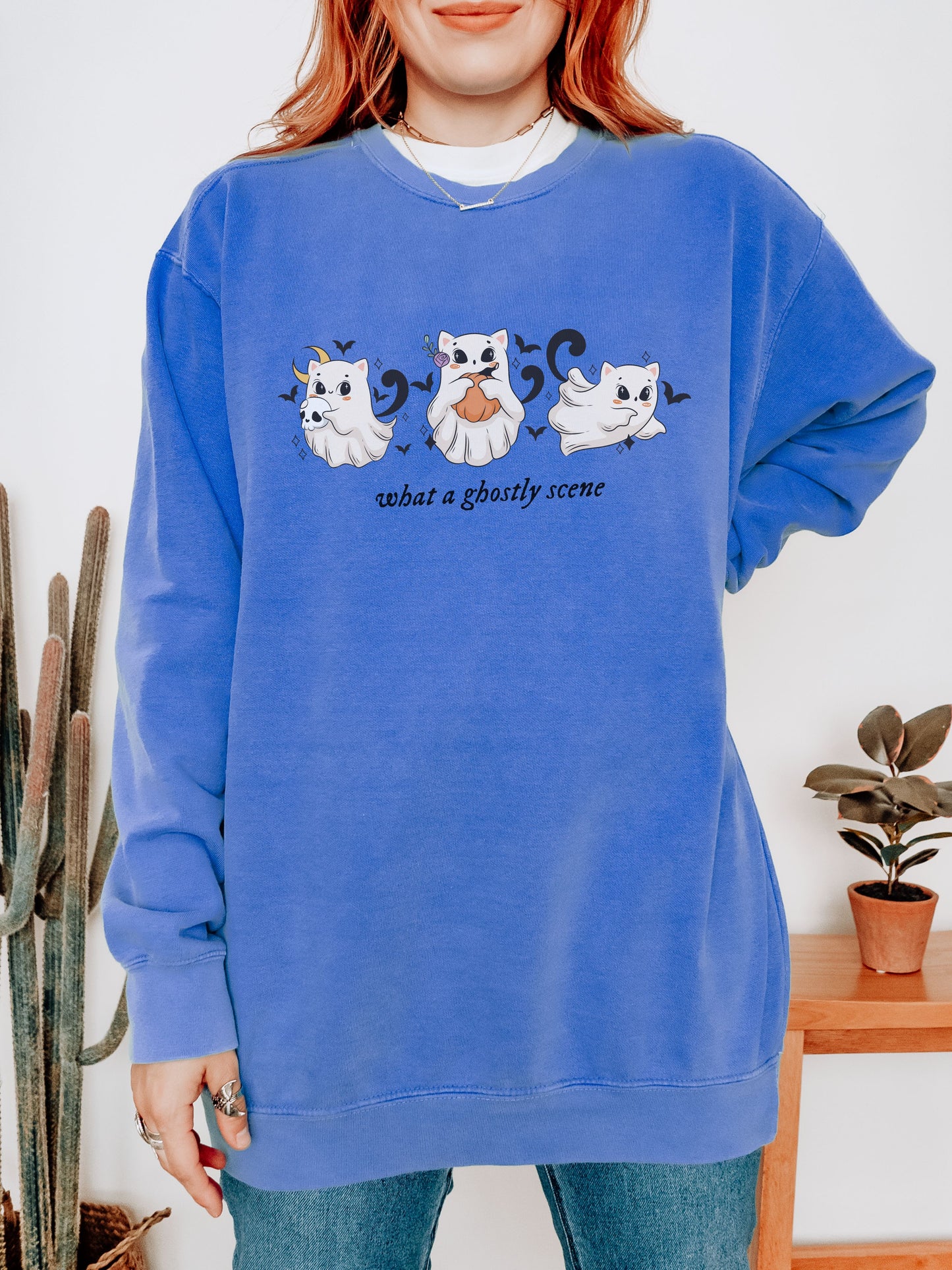 Person wearing a blue sweatshirt with ghost illustrations and text indoors.