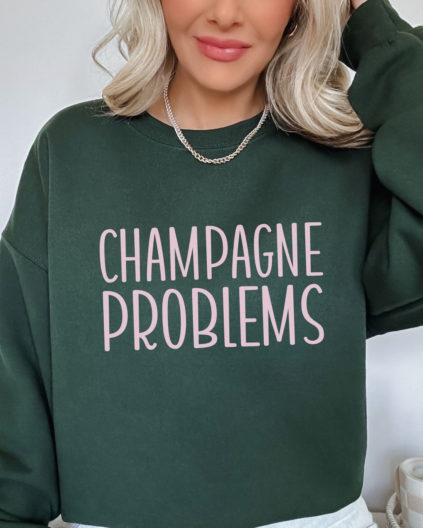 Person wearing a green sweatshirt with 'CHAMPAGNE PROBLEMS' text.