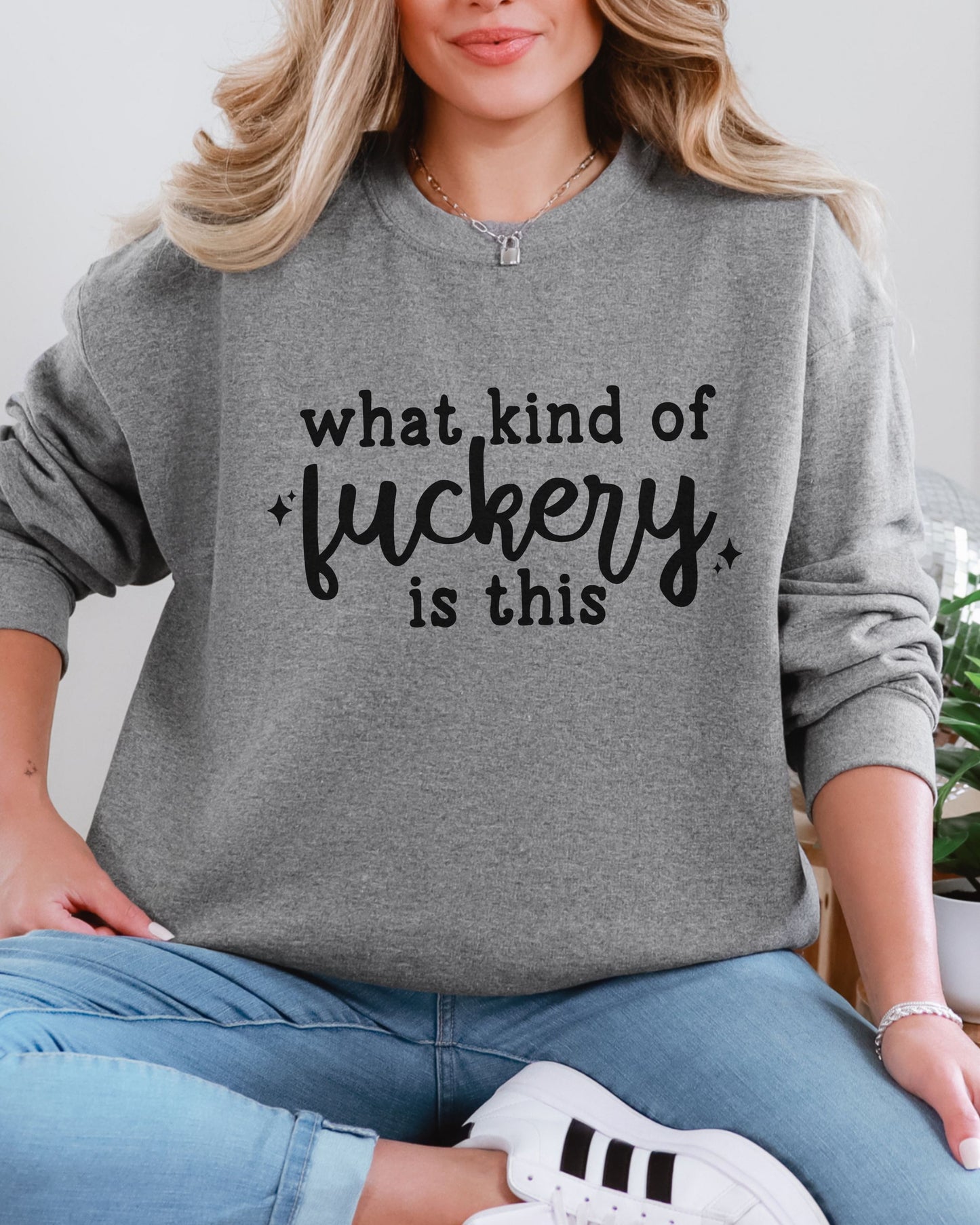 Person wearing a gray sweatshirt with text, sitting on a white surface.