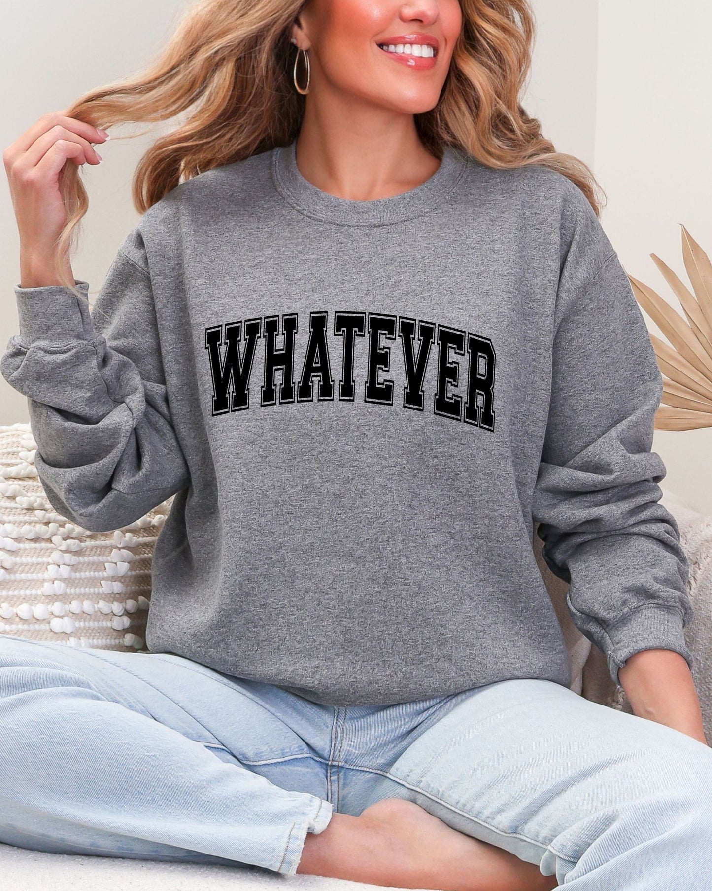 Person wearing a gray sweatshirt with 'WHATEVER' text, sitting on a couch.