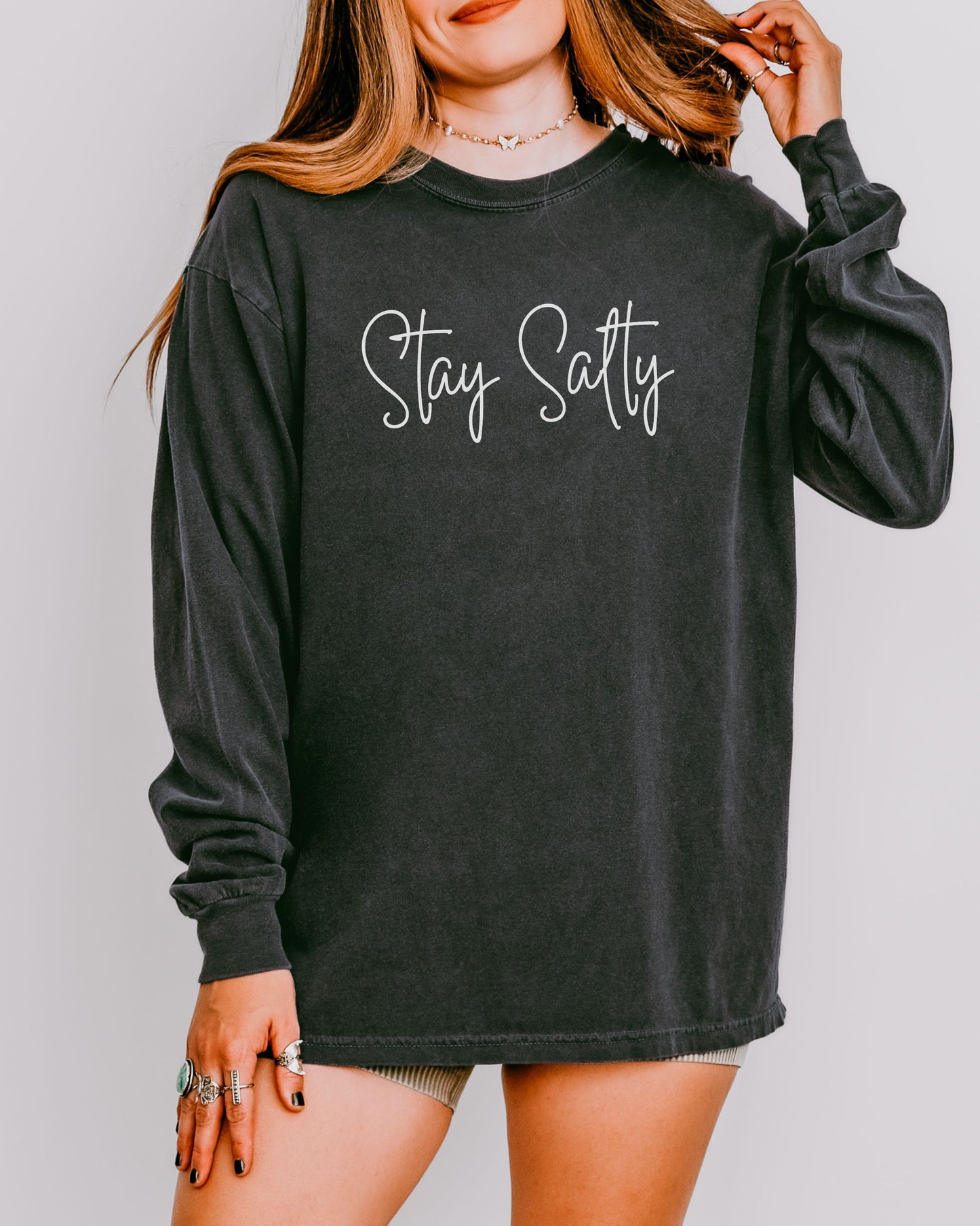 Person wearing a black long-sleeve shirt with 'Stay Satty' text on a plain background