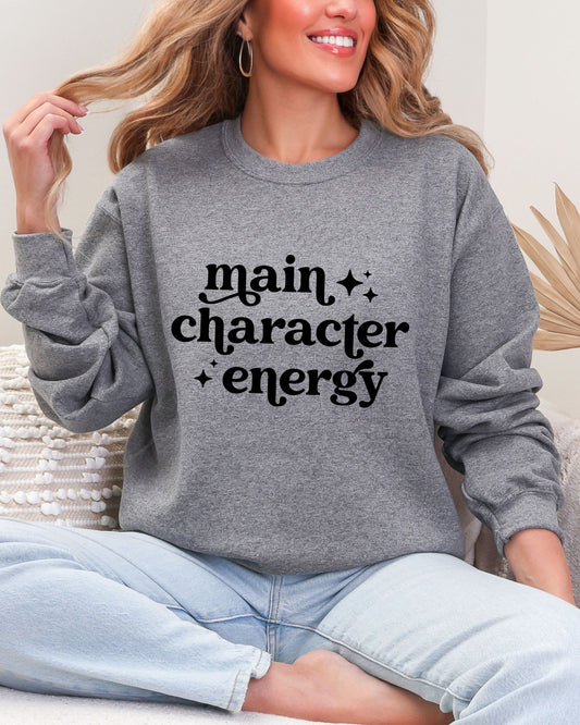 Person wearing a gray sweatshirt with 'main character energy' text