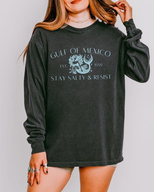 Person wearing a black long-sleeve shirt with 'Gulf of Mexico' and 'Stay Salty & Resist' text.