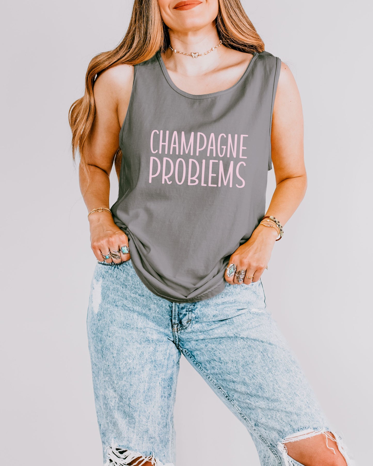 Woman wearing a gray tank top with 'Champagne Problems' text on a plain background