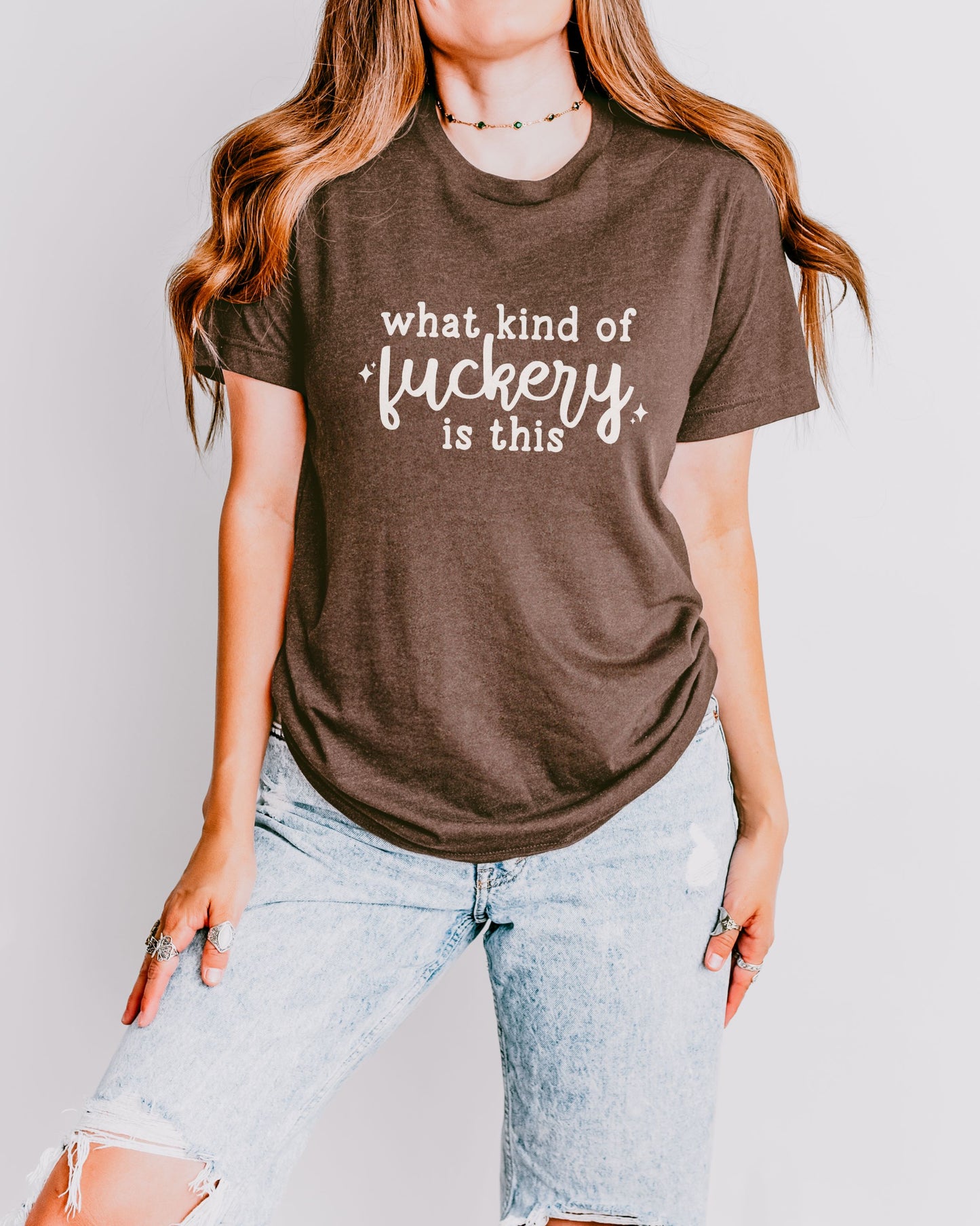 Person wearing a brown t-shirt with text, standing against a plain background