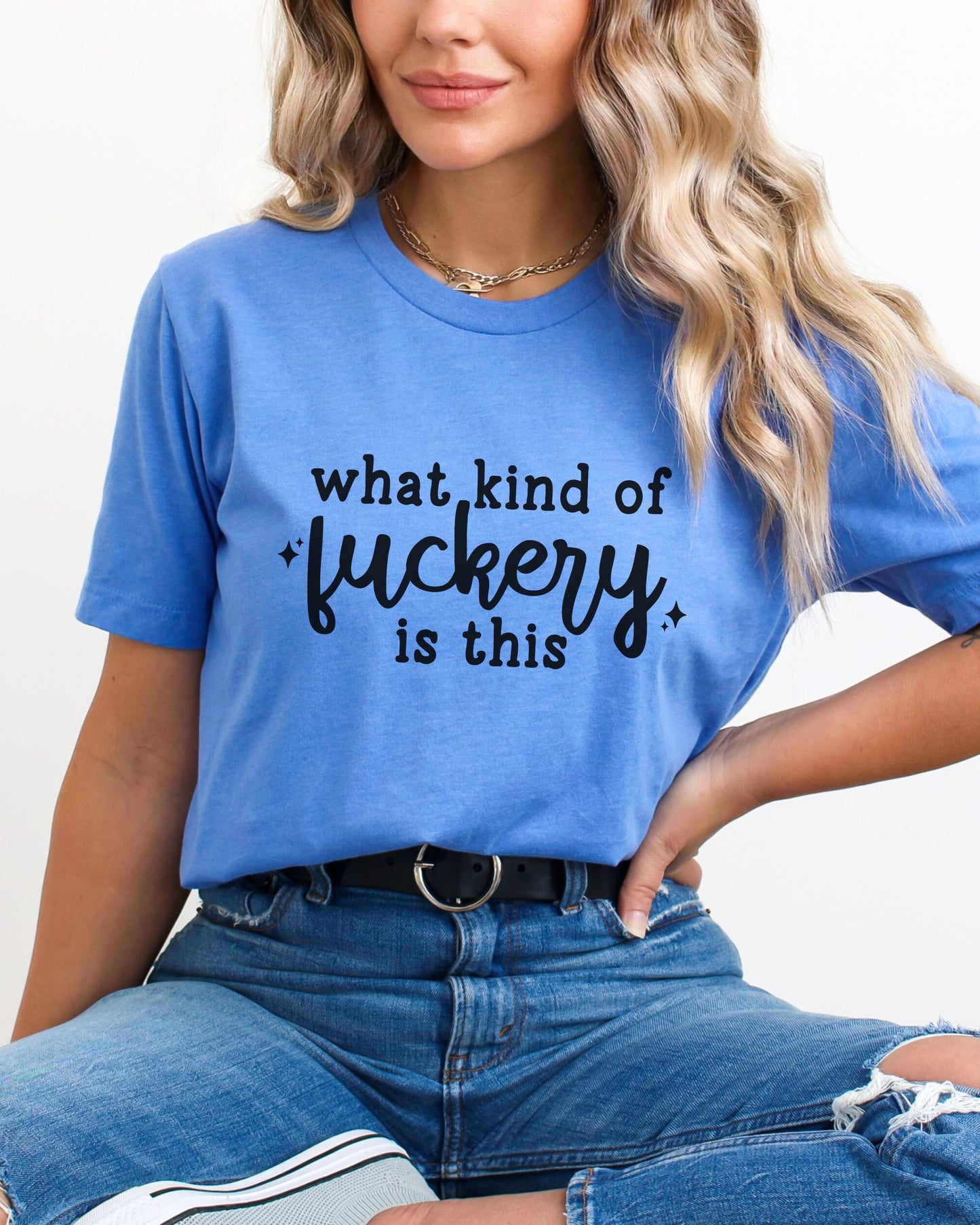 Person wearing a blue t-shirt with text, sitting against a plain background