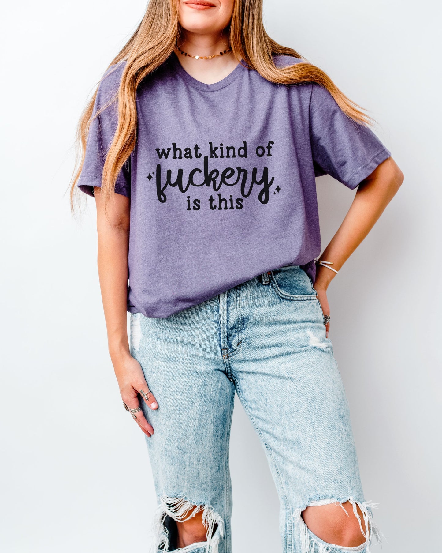 Person wearing a purple t-shirt with text and ripped jeans on a plain background