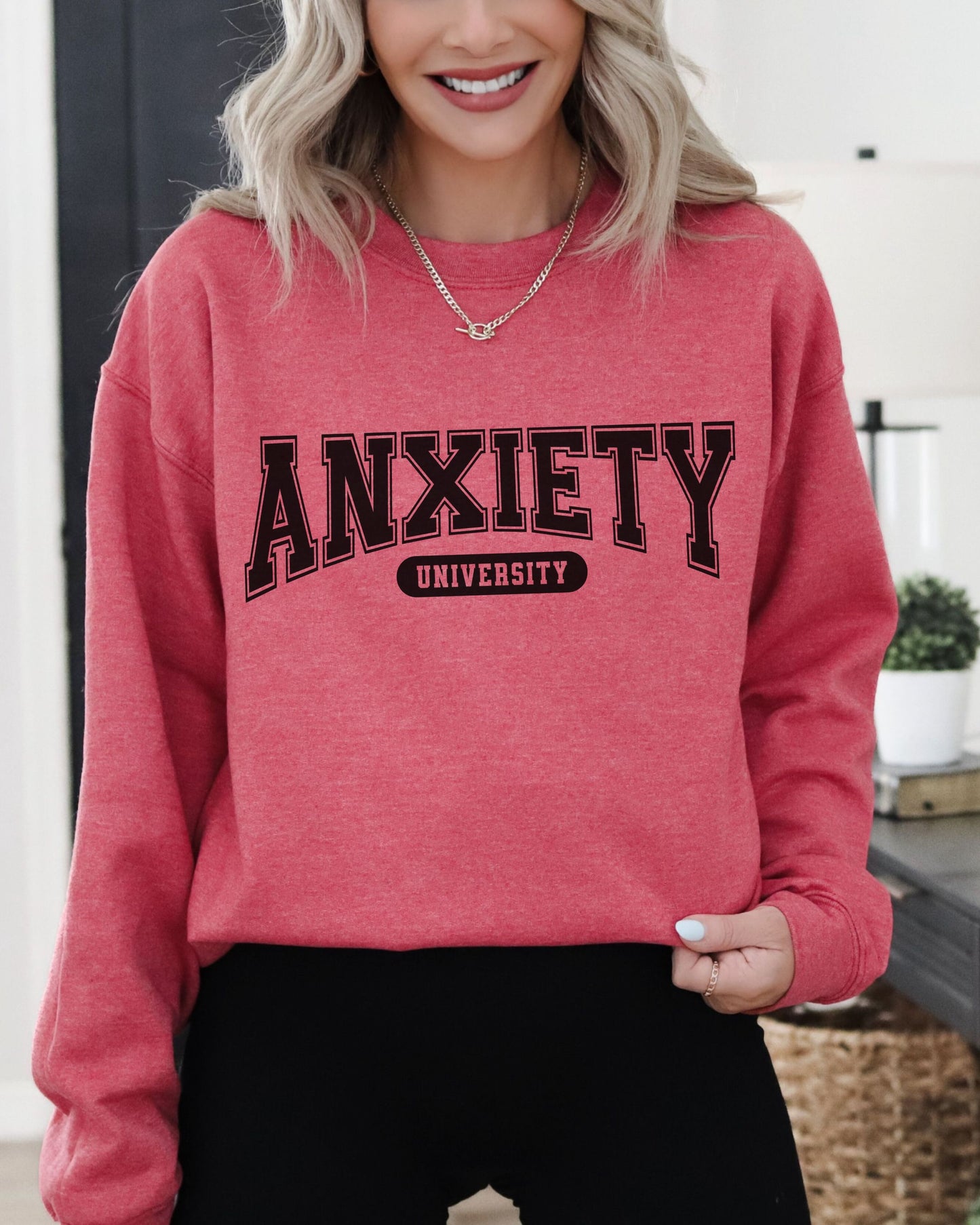 Person wearing a red sweatshirt with 'ANXIETY UNIVERSITY' text indoors.