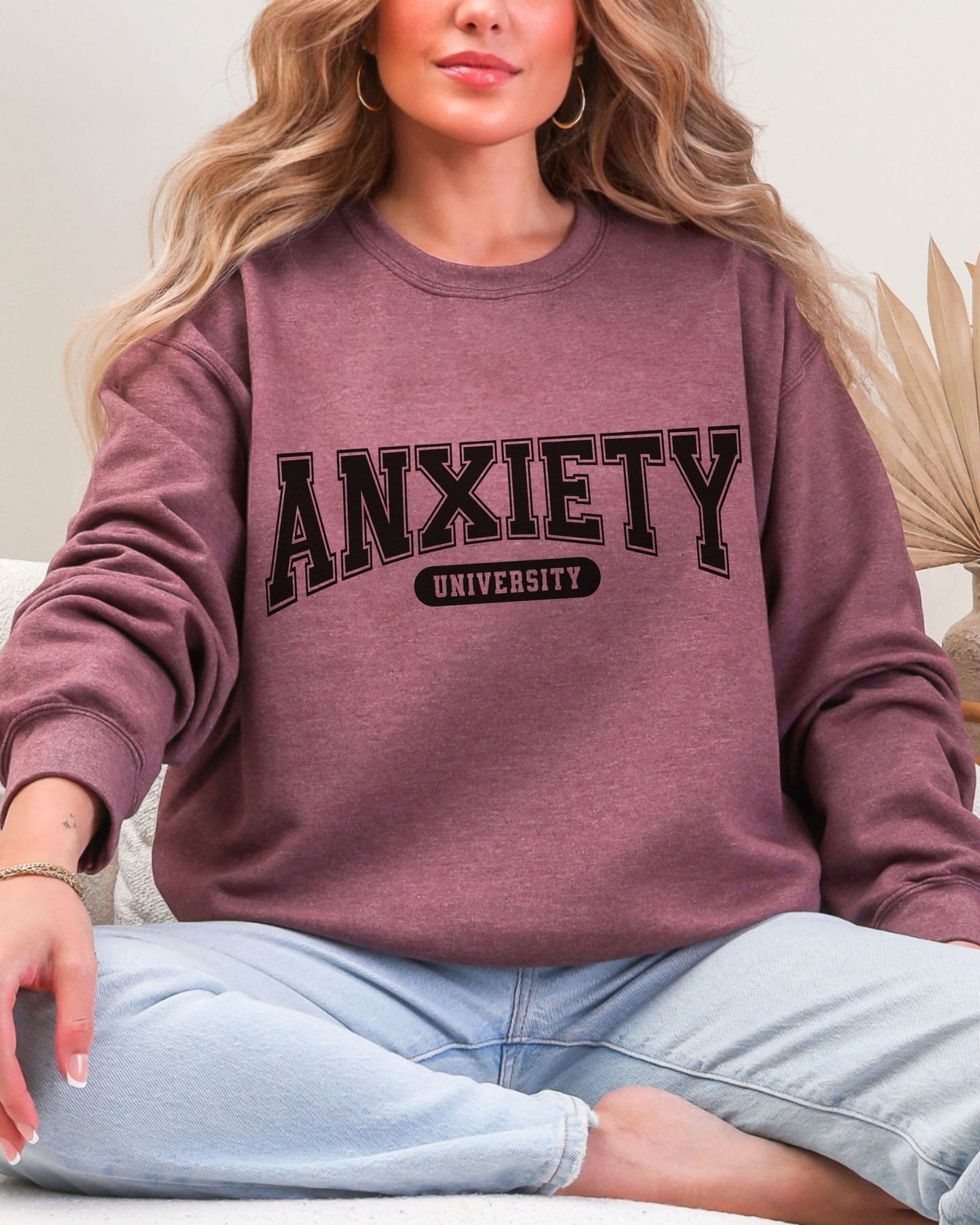 Person wearing a maroon sweatshirt with 'ANXIETY UNIVERSITY' text.