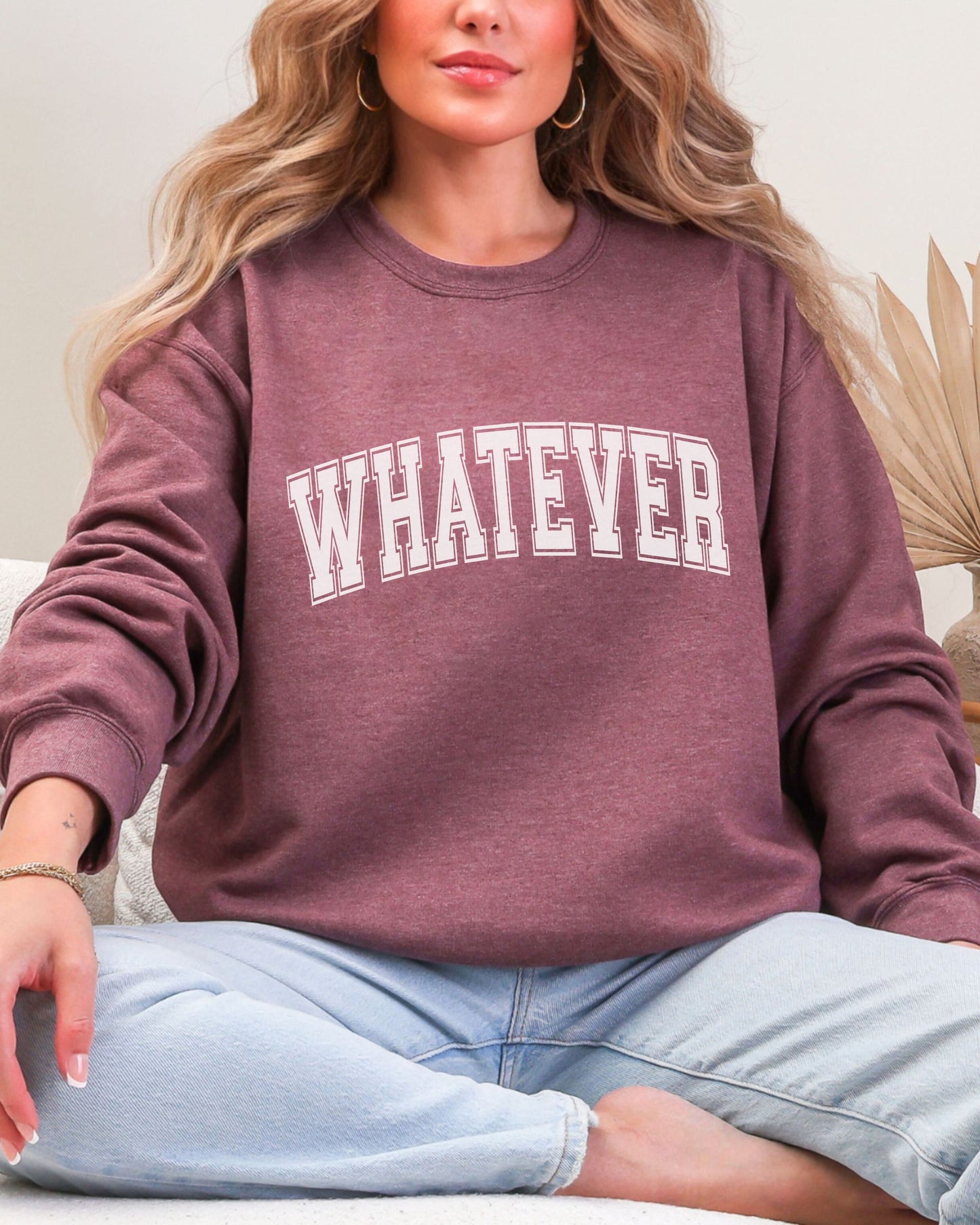 Person wearing a maroon sweatshirt with 'WHATEVER' text, sitting on a couch.